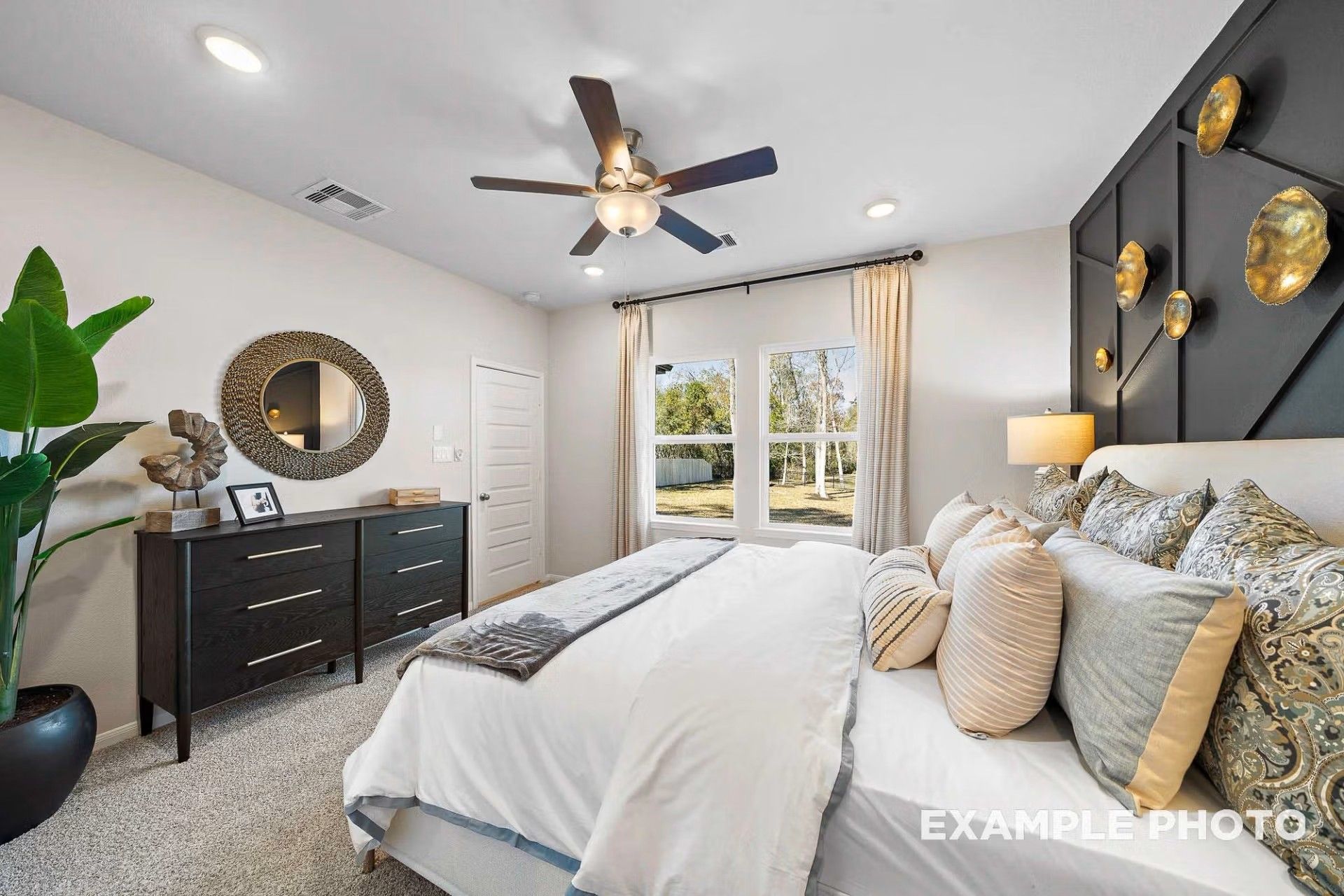 Modern primary bedroom with black accent wall, king bed, and dresser in The San Marcos E by Davidson Homes in Heartland, TX.