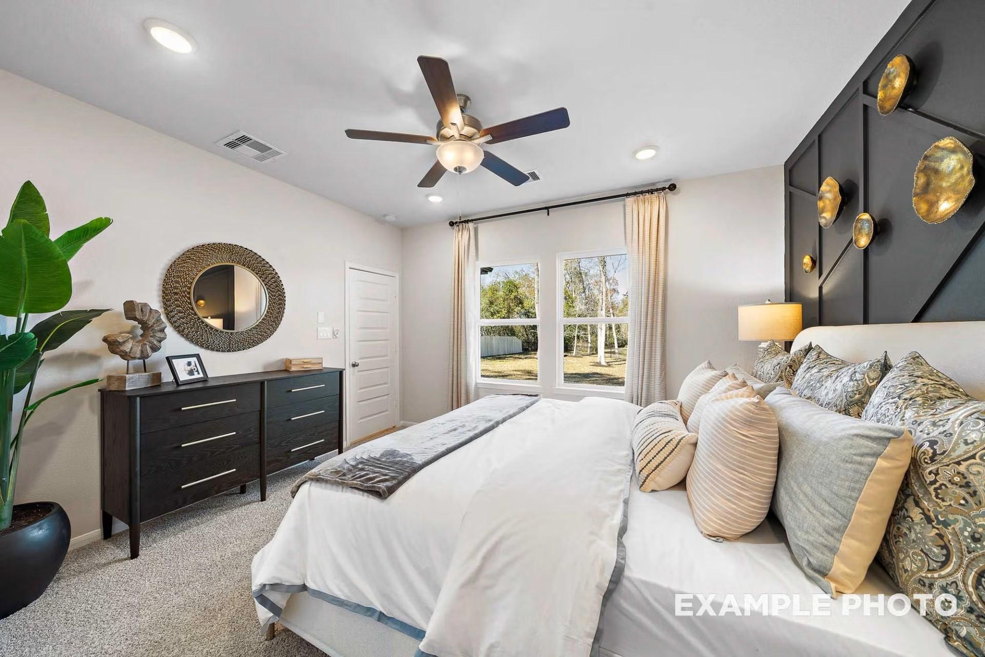 Modern primary bedroom with black accent wall, king bed, and dresser in The San Marcos E by Davidson Homes in Heartland, TX.