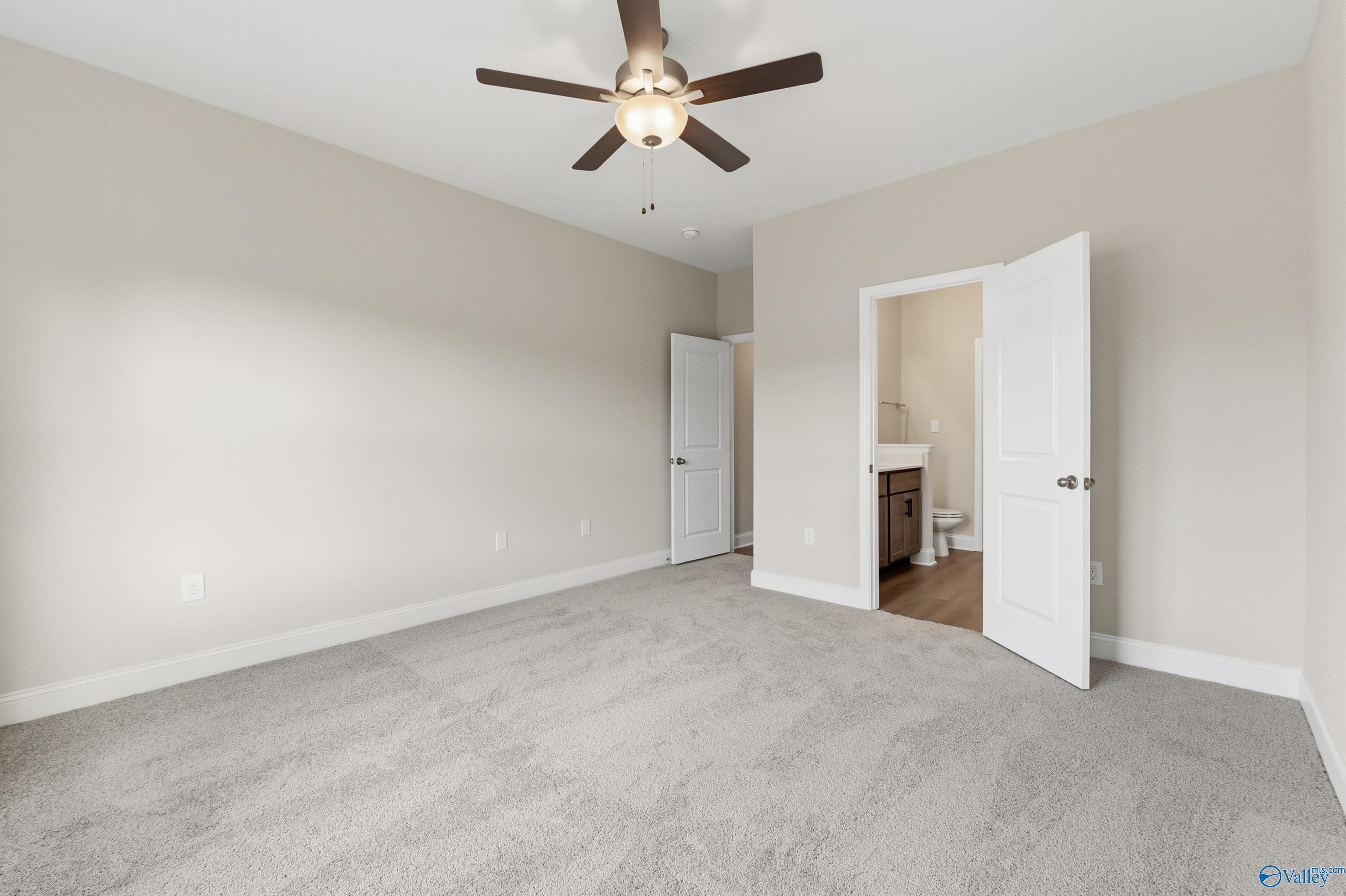 Bright secondary bedroom with beige walls, ceiling fan, carpet floor, and adjacent bath in Davidson Homes Asheville C, Huntsville AL