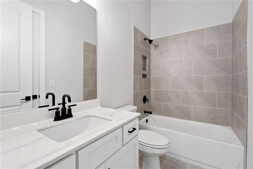 Modern bathroom with white shaker vanity, black faucet, gray tile tub-shower combo in Davidson Homes Seaside B, Woodstock GA