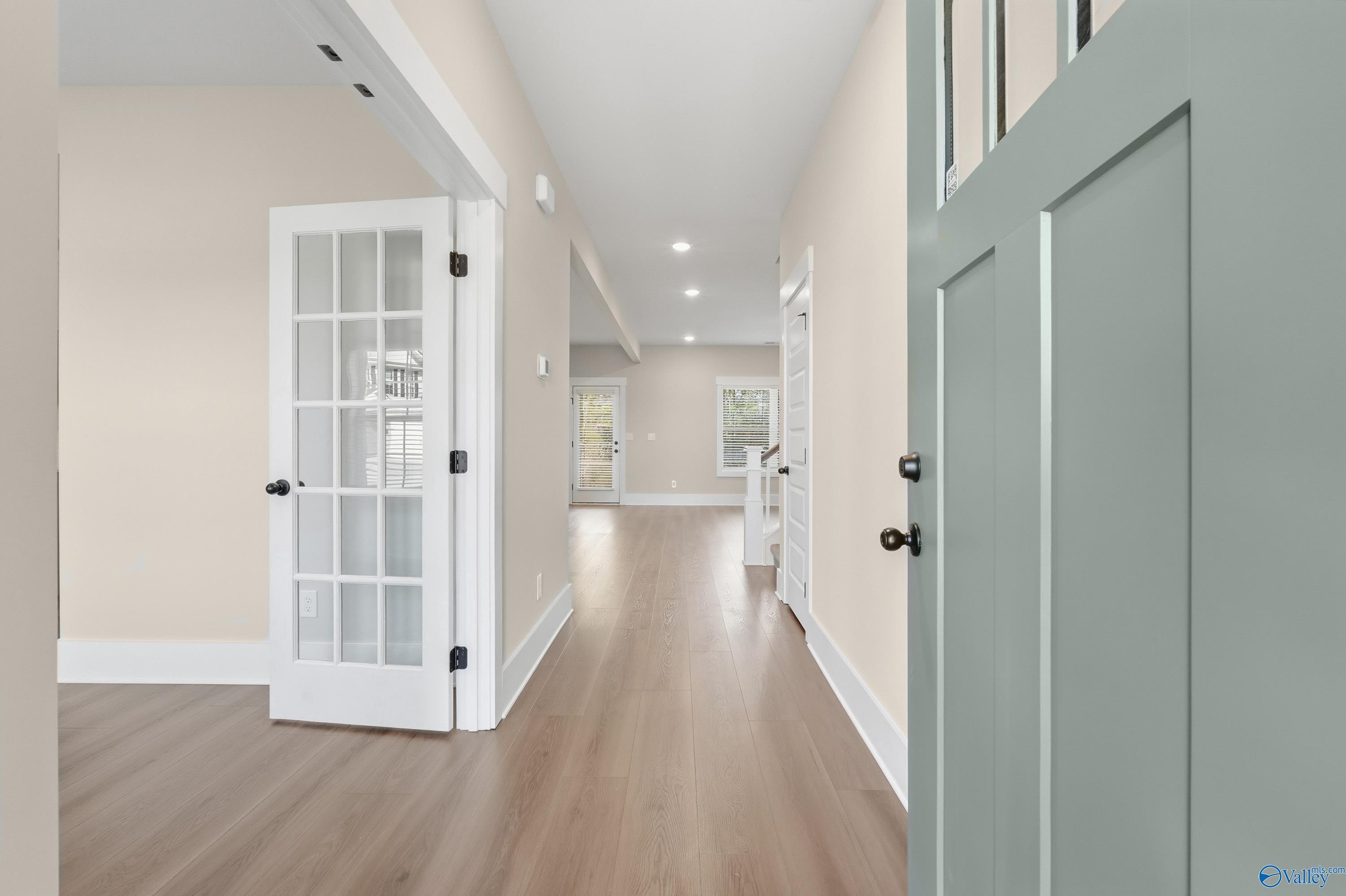 Bright entry hallway with hardwood floors, open French doors, and sage green front door in Davidson Homes Shelby A, Athens AL