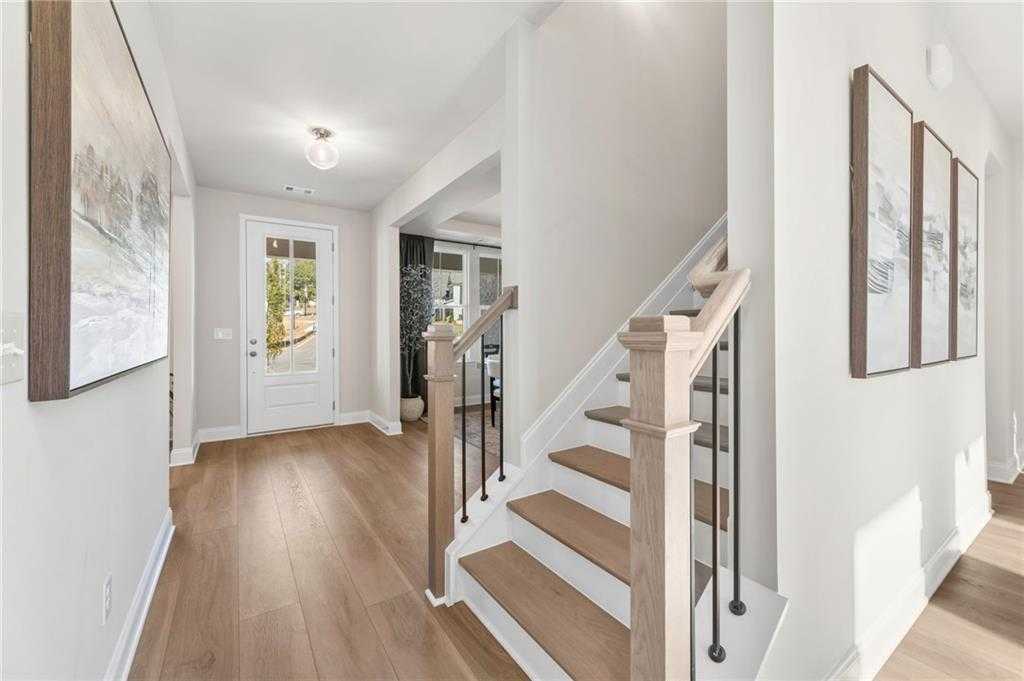 Welcoming foyer with oak staircase, hardwood floors, and wall art in The Danbury C 5-bedroom home, Buford, Georgia
