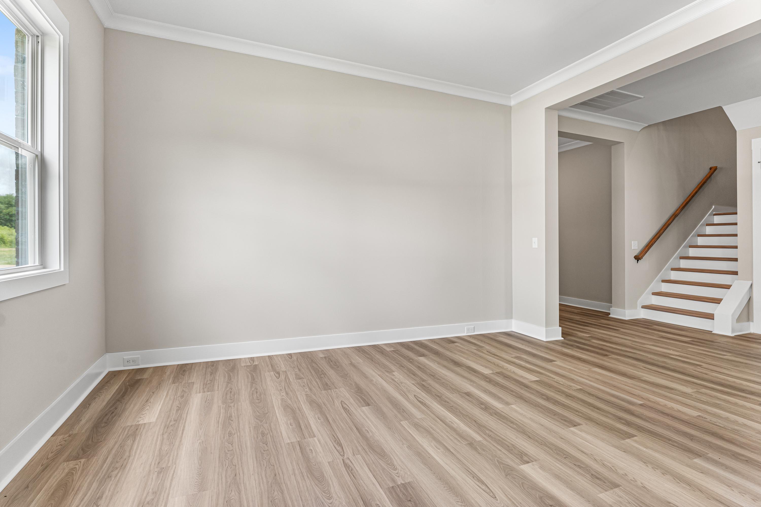 Spacious foyer in The Oxford A Evermore Homes design with beige walls, hardwood floors, large windows, and ascending staircase
