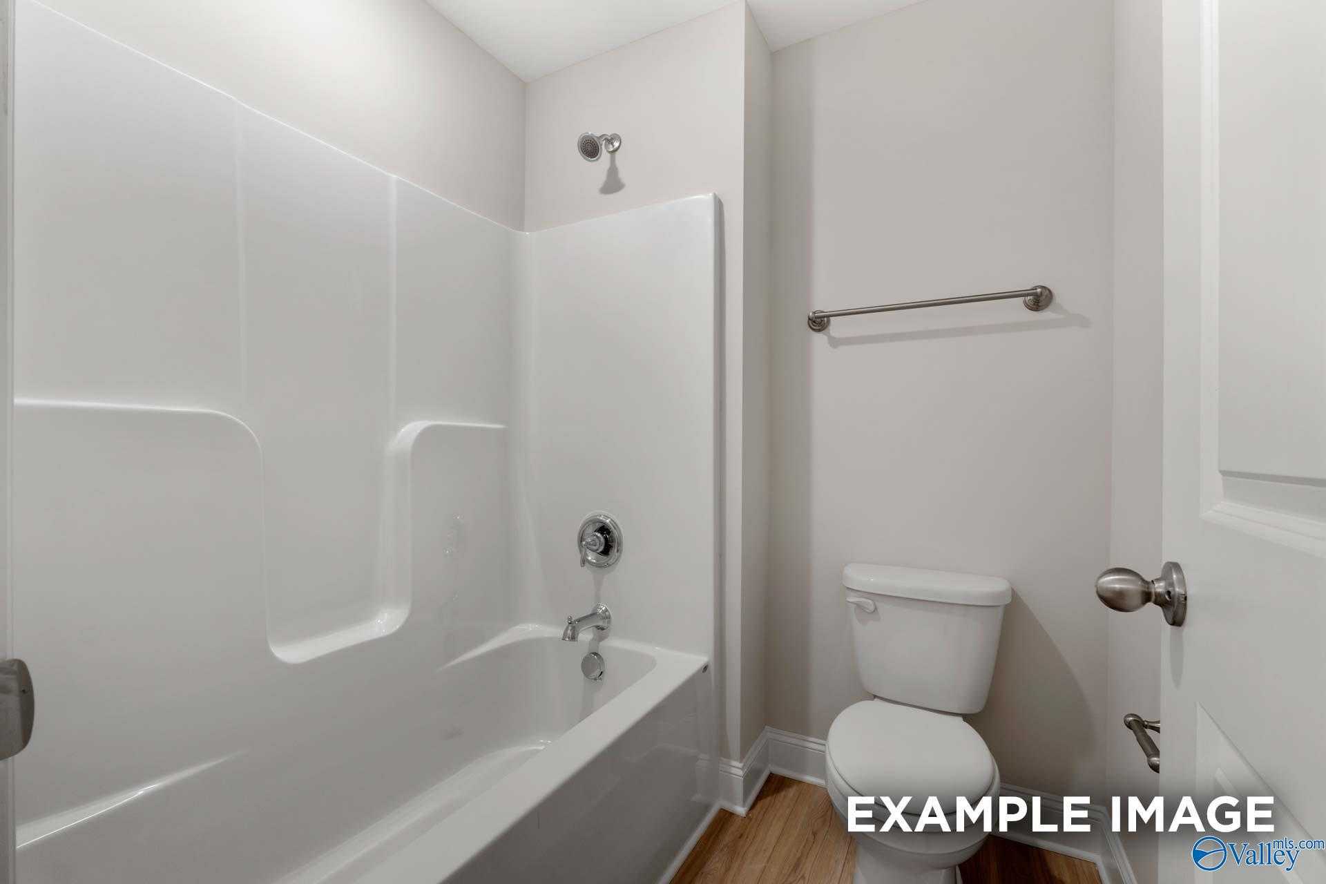 Modern bathroom with white subway tile tub-shower combo, toilet, and hardwood floors in Davidson Homes The Camden, Huntsville