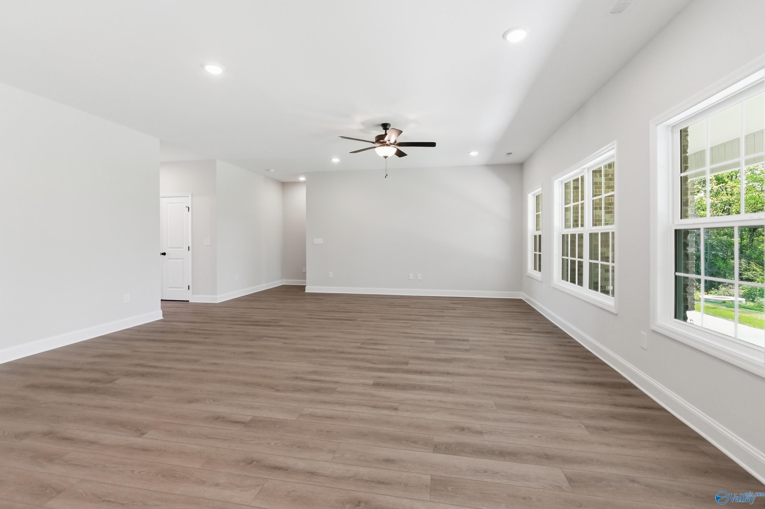 Spacious living room with ceiling fan, recessed lights, large windows to green yard, and hardwood floors in Davidson Homes The Rockford B, Athens AL