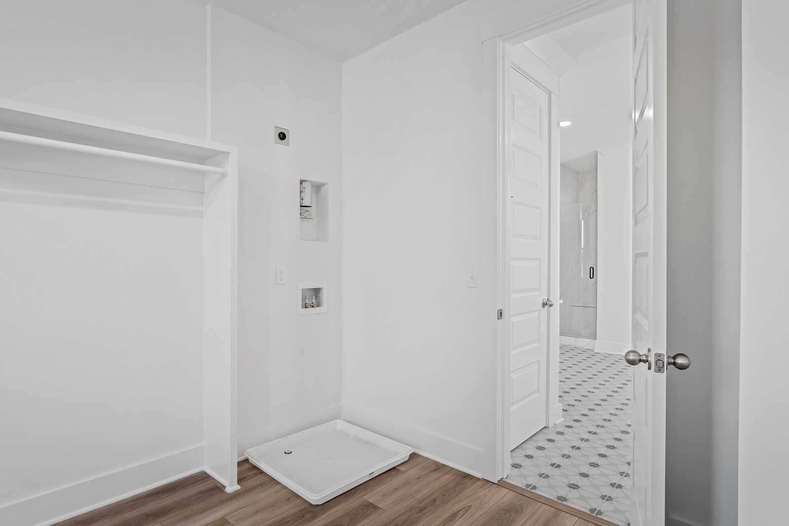 Bright laundry room with utility sink, storage shelves, and adjacent bathroom in Davidson Homes The Alston A, Murfreesboro, TN