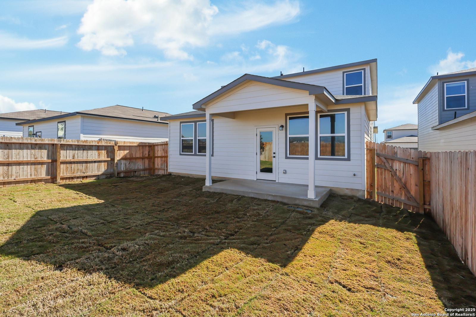 Covered back patio and fenced grassy backyard of two-story Davidson Homes The Brazos C in Applewhite Meadows, San Antonio