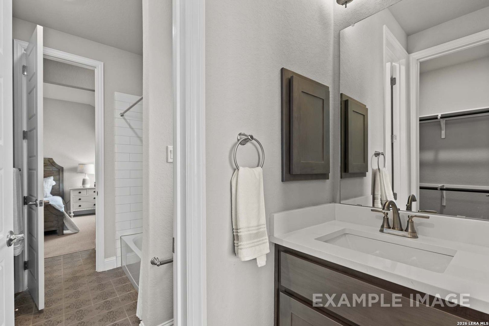 Modern bathroom vanity with white countertop and dark cabinetry in The Garner C plan at The Reserve at Potranco Oaks.