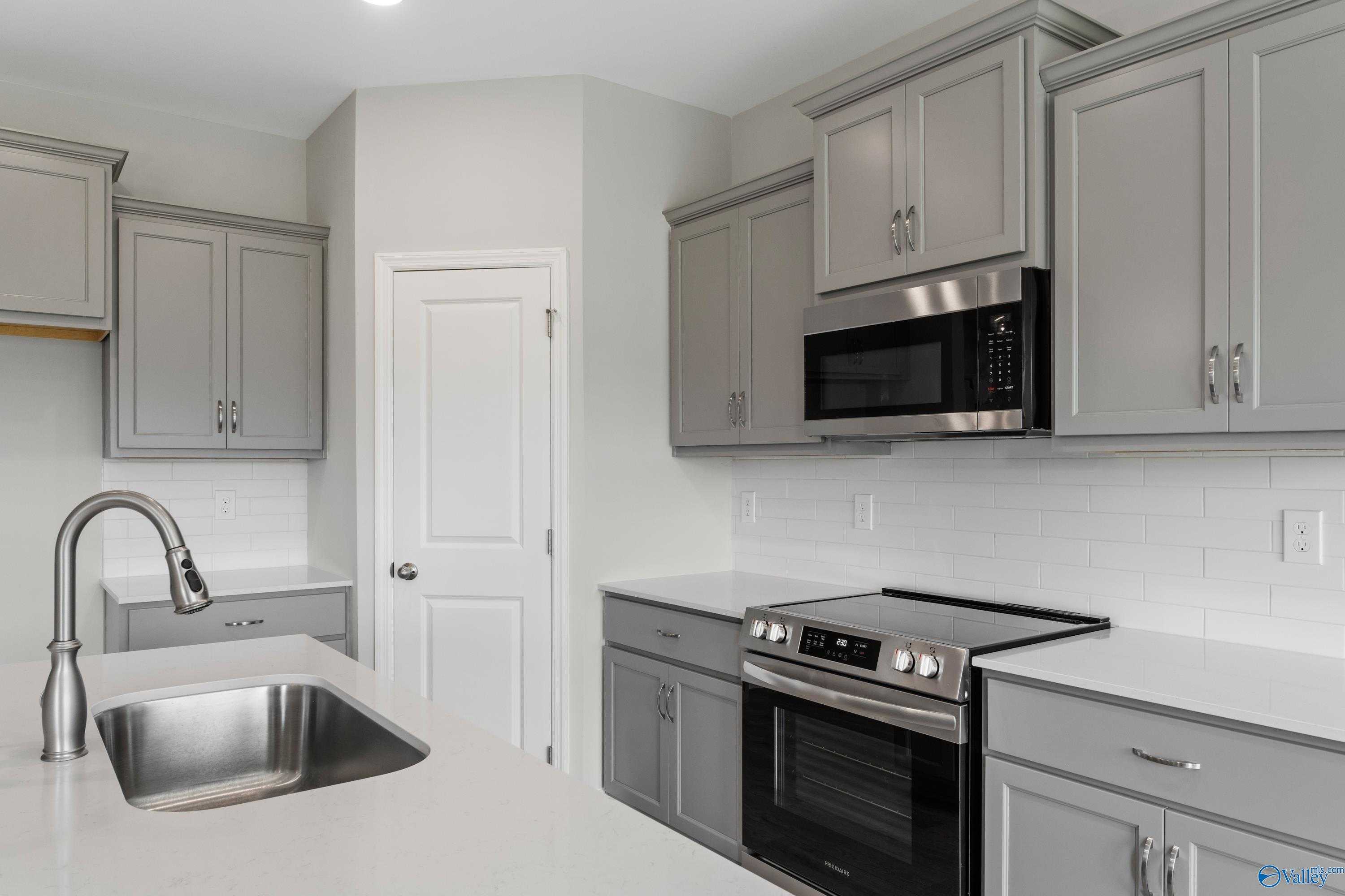 Modern kitchen featuring stainless steel range, microwave, gray shaker cabinets, subway tile backsplash in Davidson Homes The Asheville, Meridianville, AL