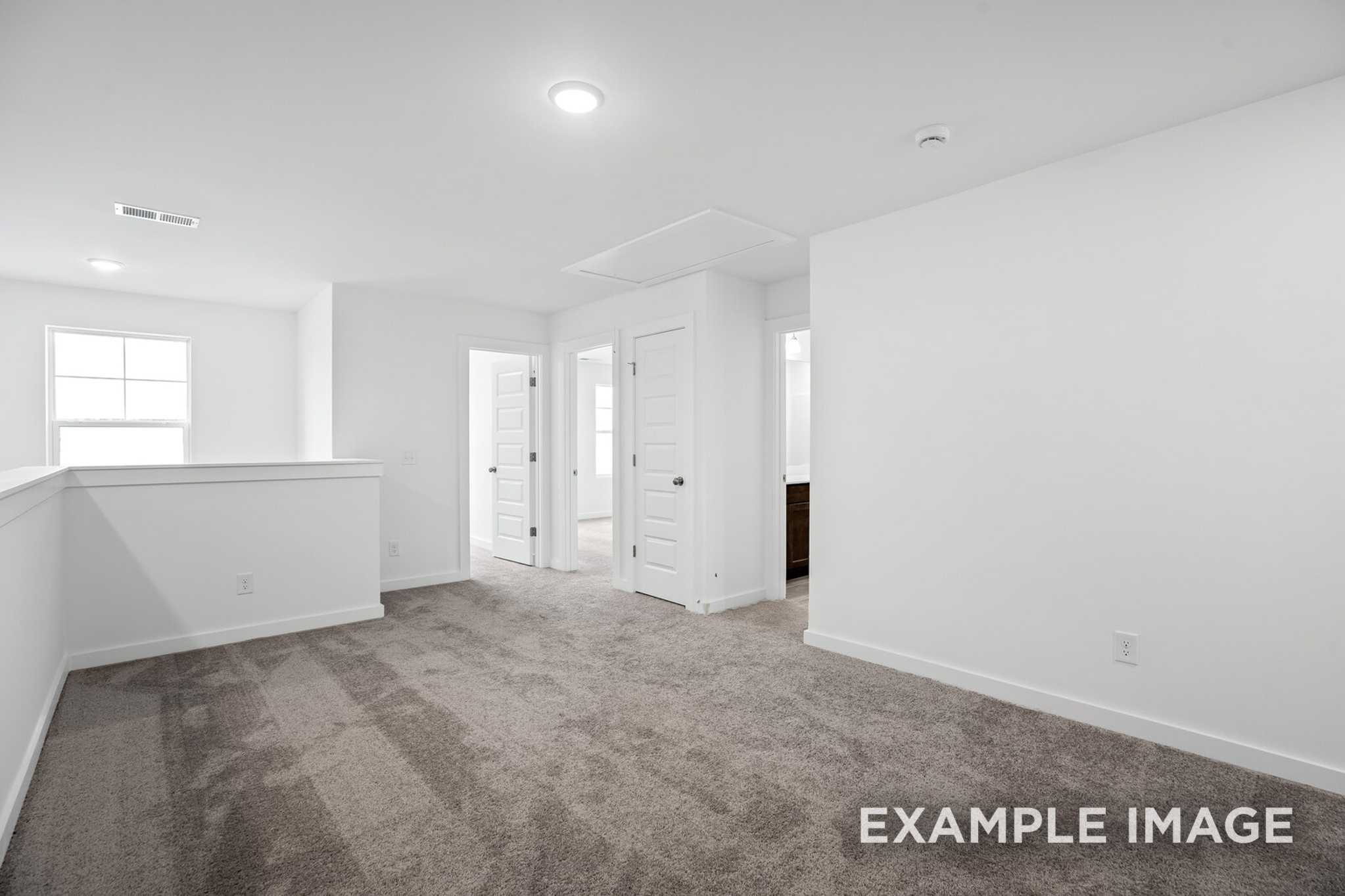 Spacious upstairs loft in The Grayson C 2-story home with gray carpet, white doors, balcony railing, and recessed lighting