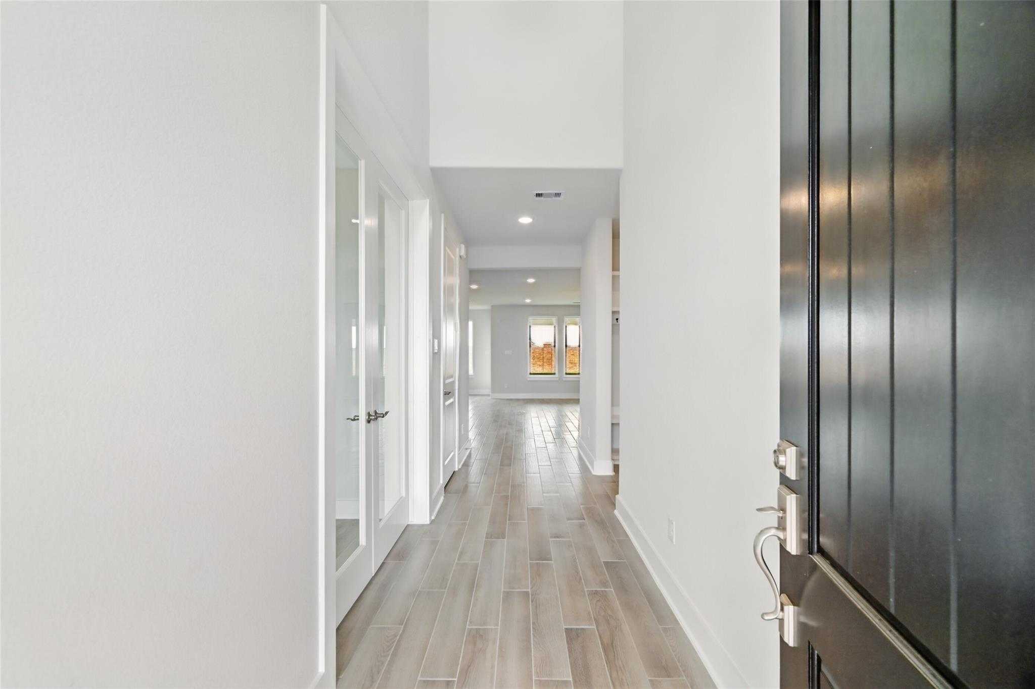 Bright entry hallway with high ceilings, frosted glass doors, and wood-look floors in Davidson Homes The Philip A, Lago Mar
