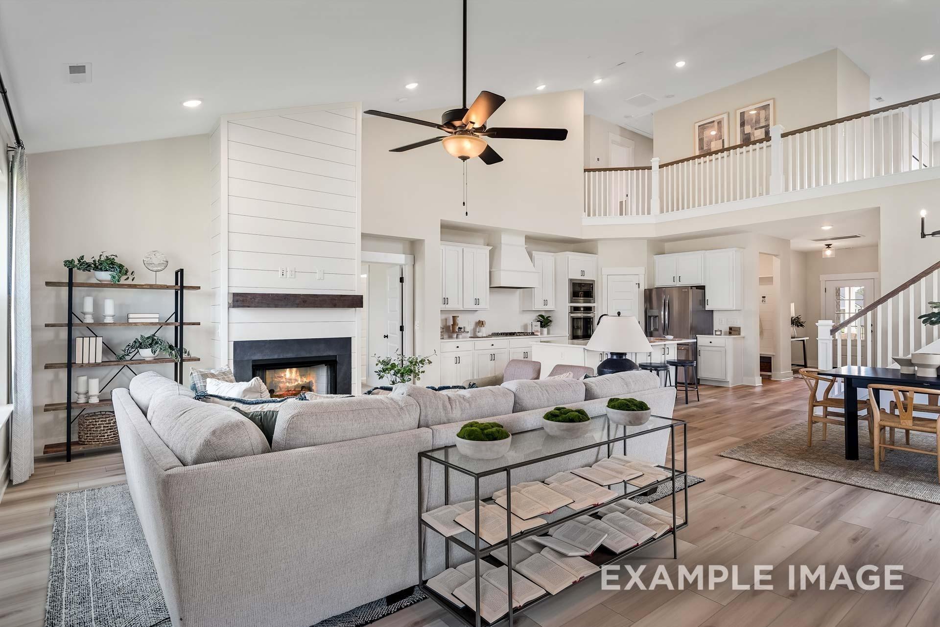 Open-concept living room with shiplap fireplace, ceiling fan, and adjacent white kitchen in Davidson Homes The Ridgeport, Gallatin, TN