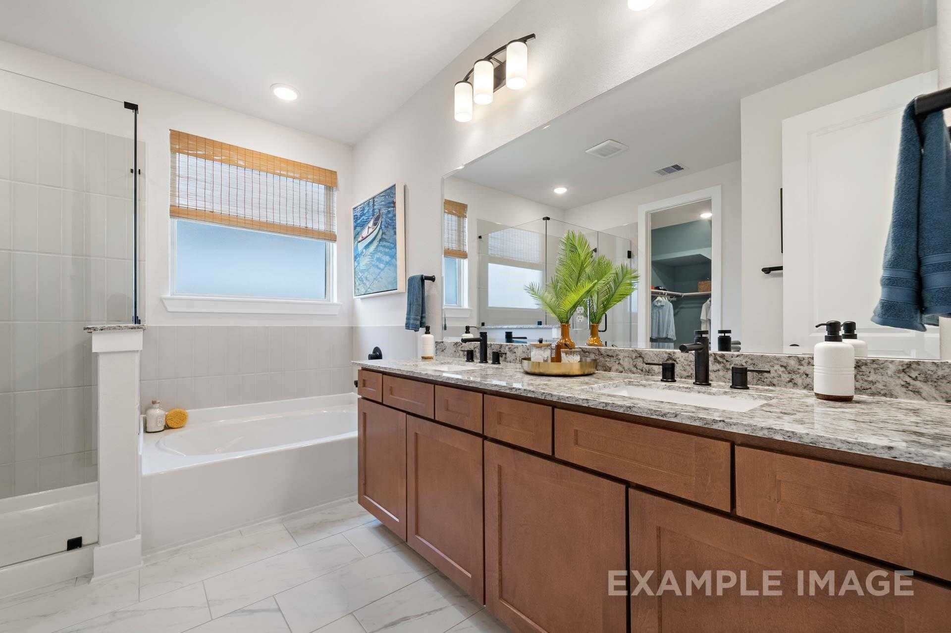 Modern master bathroom featuring soaking tub, double wood vanity with quartz countertop, and bamboo window blinds in Davidson Homes The Edward A, Texas City