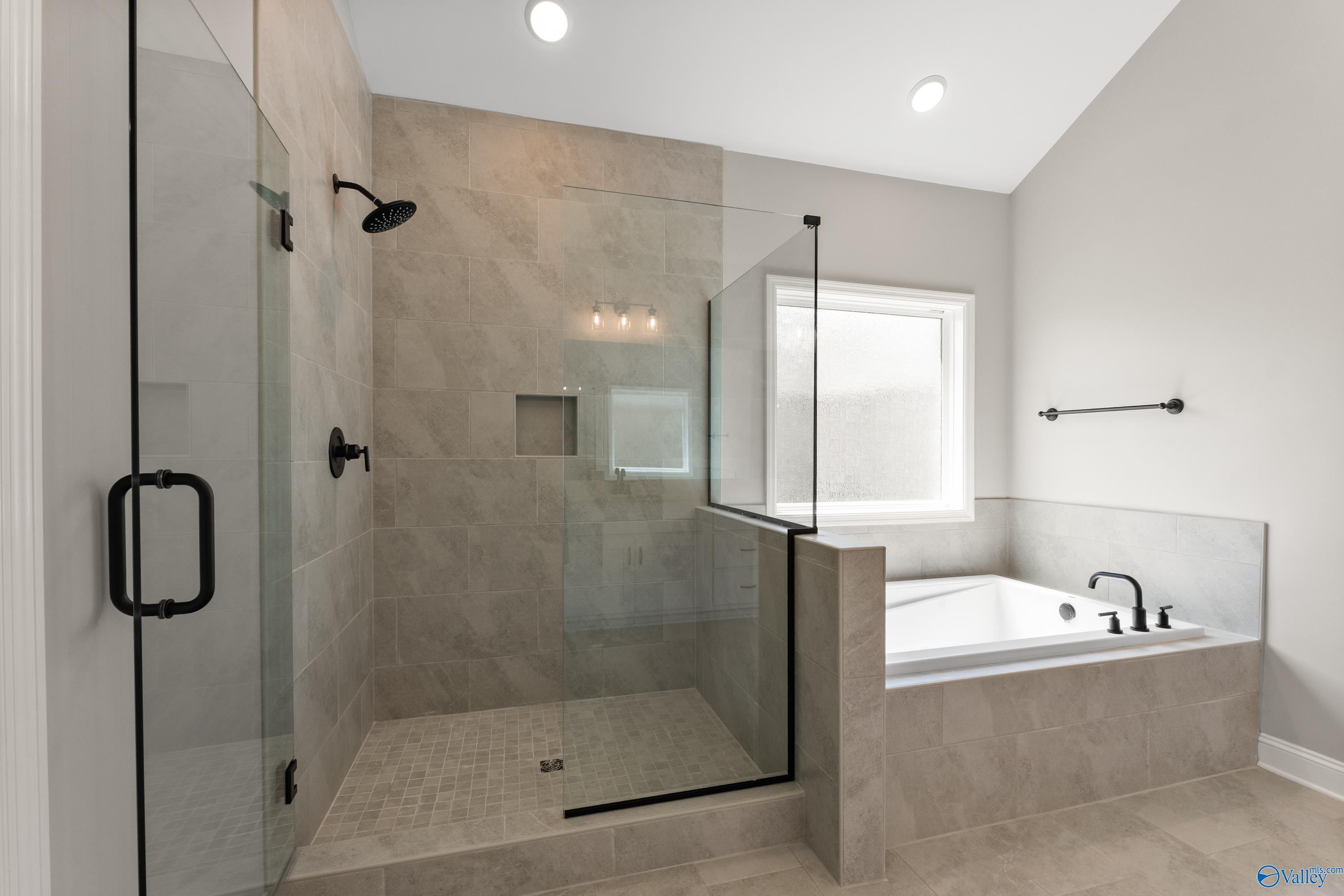 Luxurious master bathroom with frameless glass shower, soaking tub, and tiled accents in Davidson Homes The Finleigh, Toney, AL
