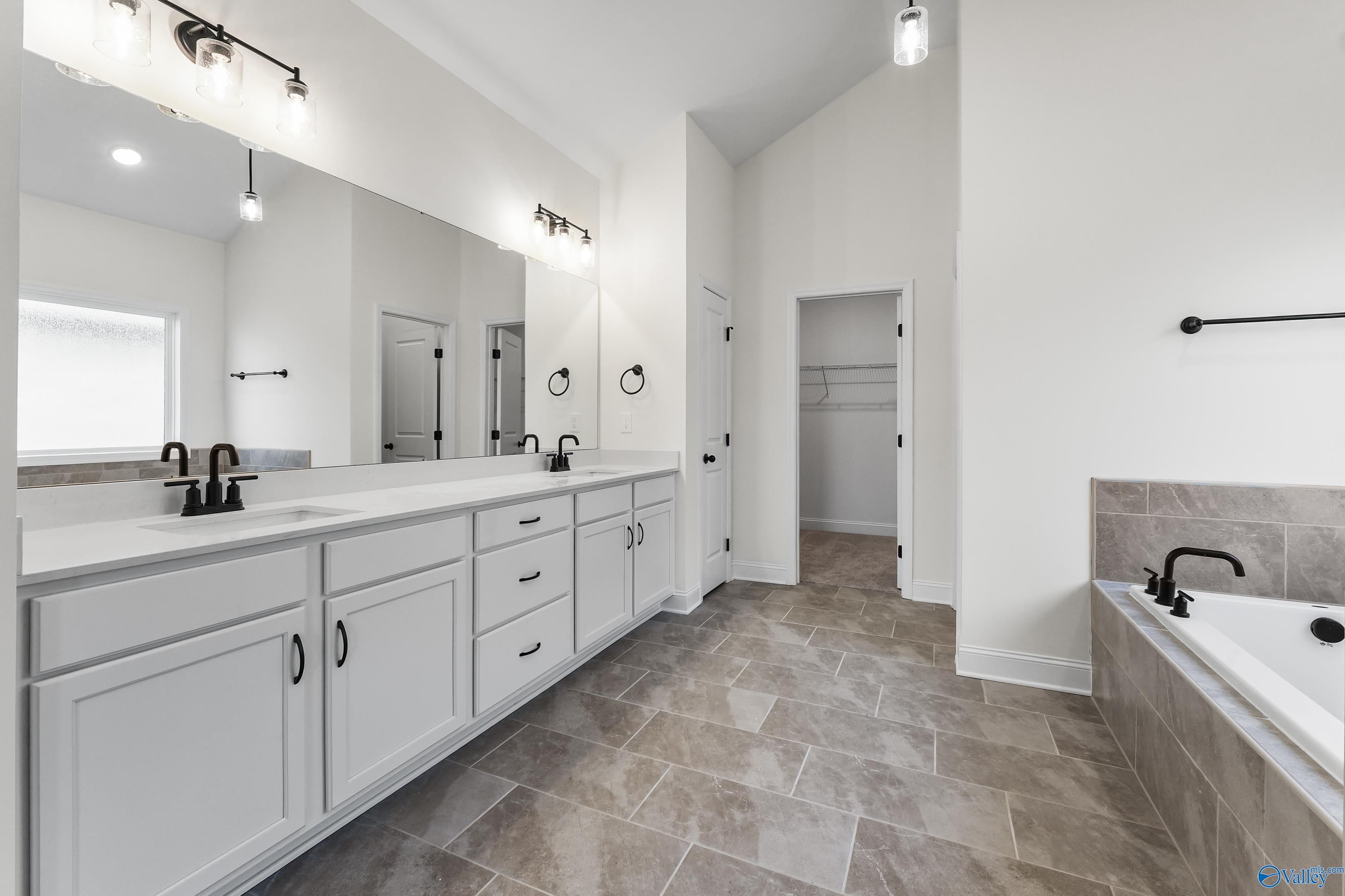 Modern master bathroom featuring double white vanity, freestanding tub, and tiled flooring in Davidson Homes The Finleigh, Harvest, Alabama