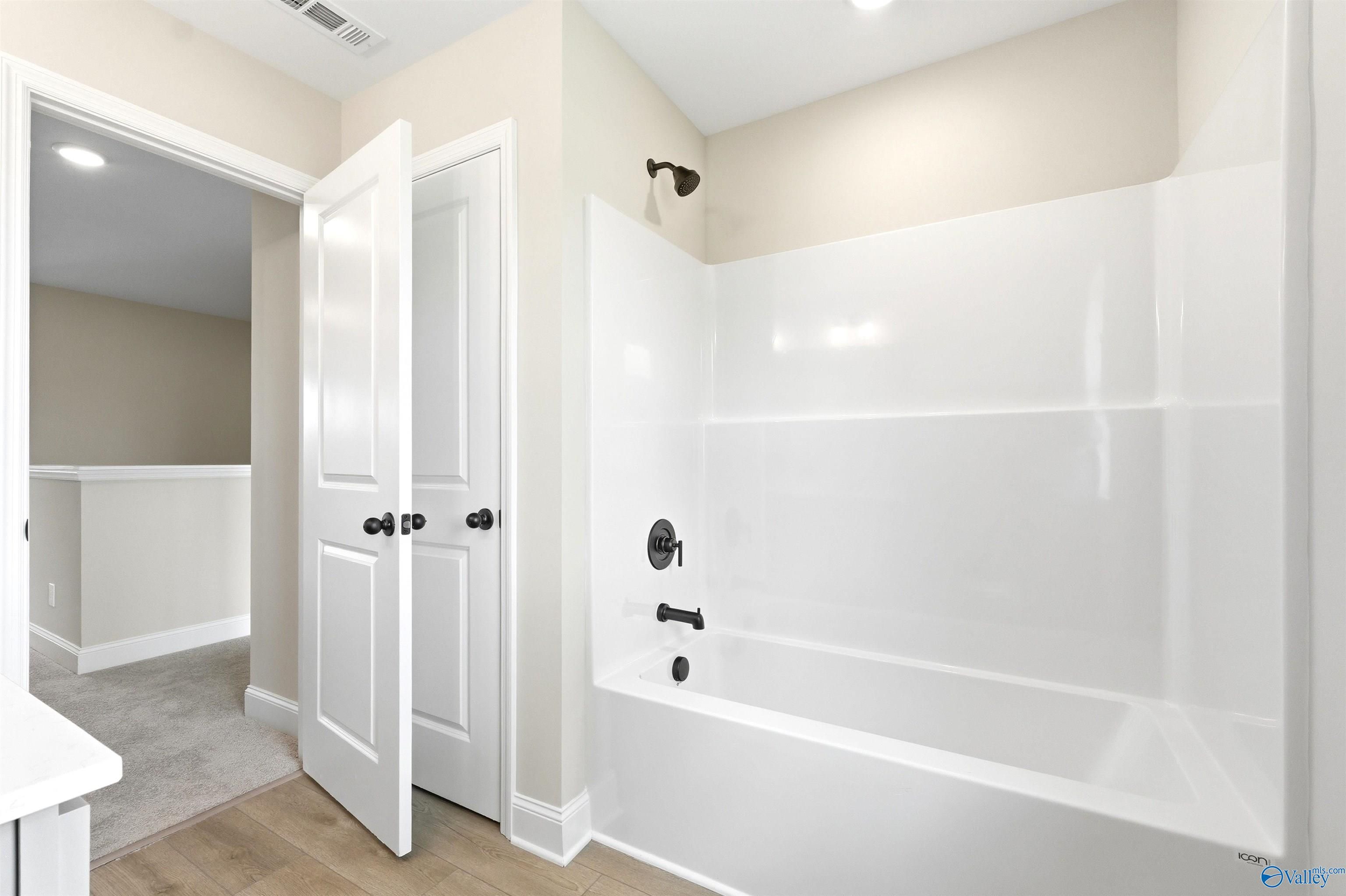 Full bathroom with white tub and shower surround in The Shelby A floor plan at Wood Trail in Toney, Alabama.