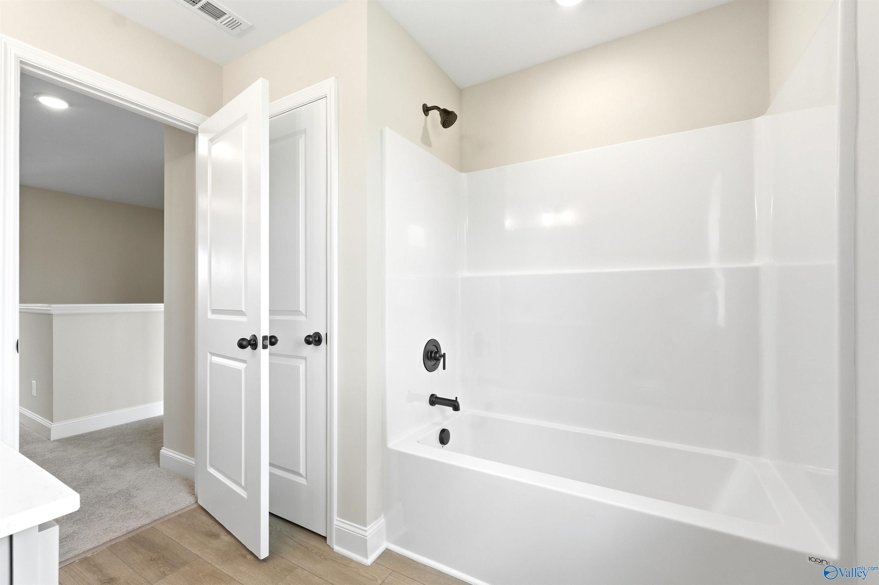 Full bathroom with white tub and shower surround in The Shelby A floor plan at Wood Trail in Toney, Alabama.