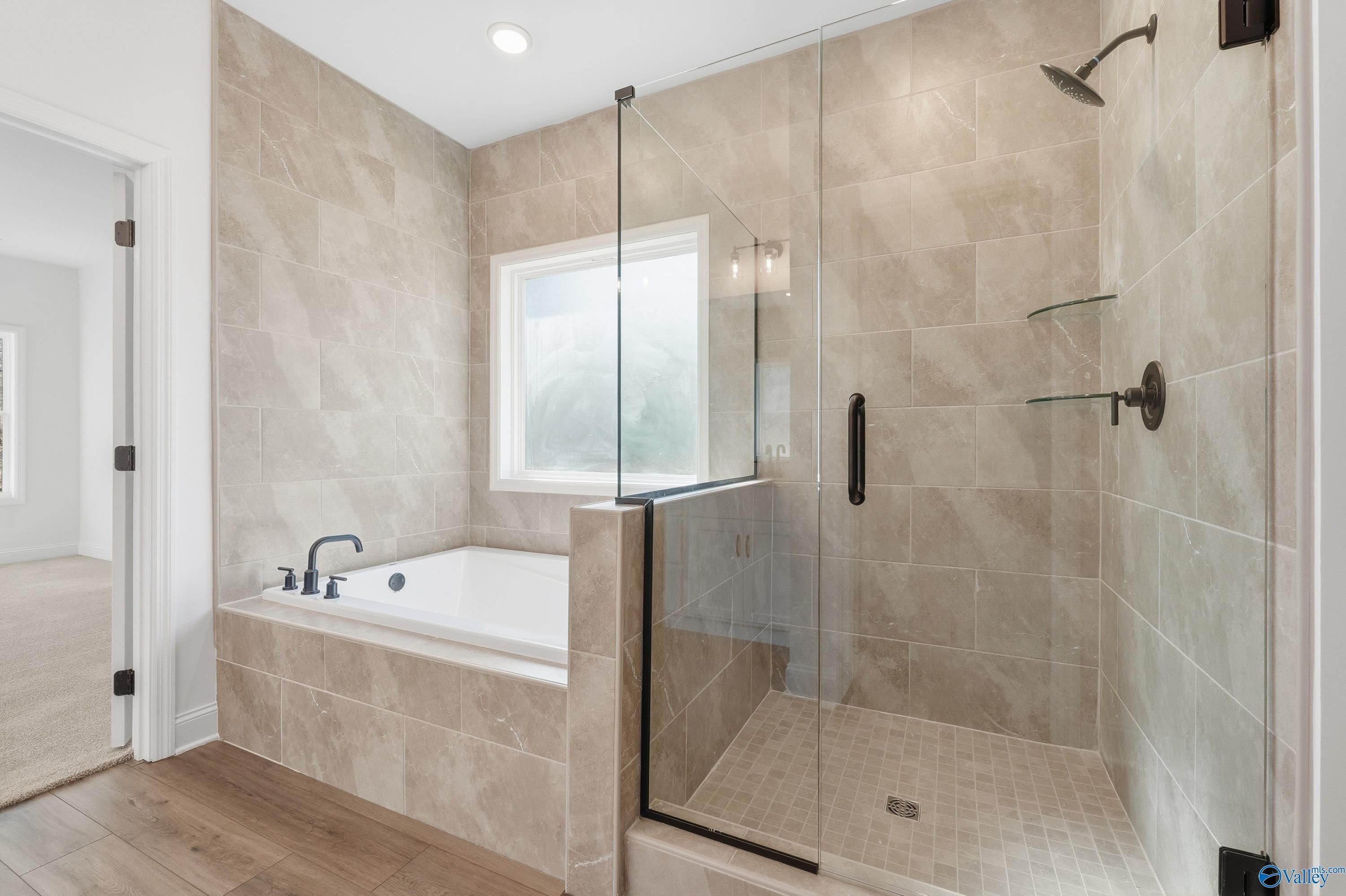 Elegant master bathroom with frameless glass shower, freestanding soaking tub, and tiled walls in Davidson Homes The Rockford D, Hazel Green, AL
