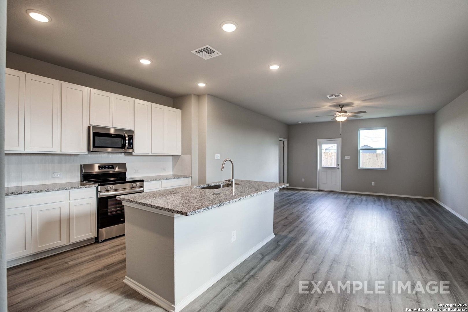 Modern open-concept kitchen with white shaker cabinets, granite island, stainless appliances in Davidson Homes The Blanco C, San Antonio