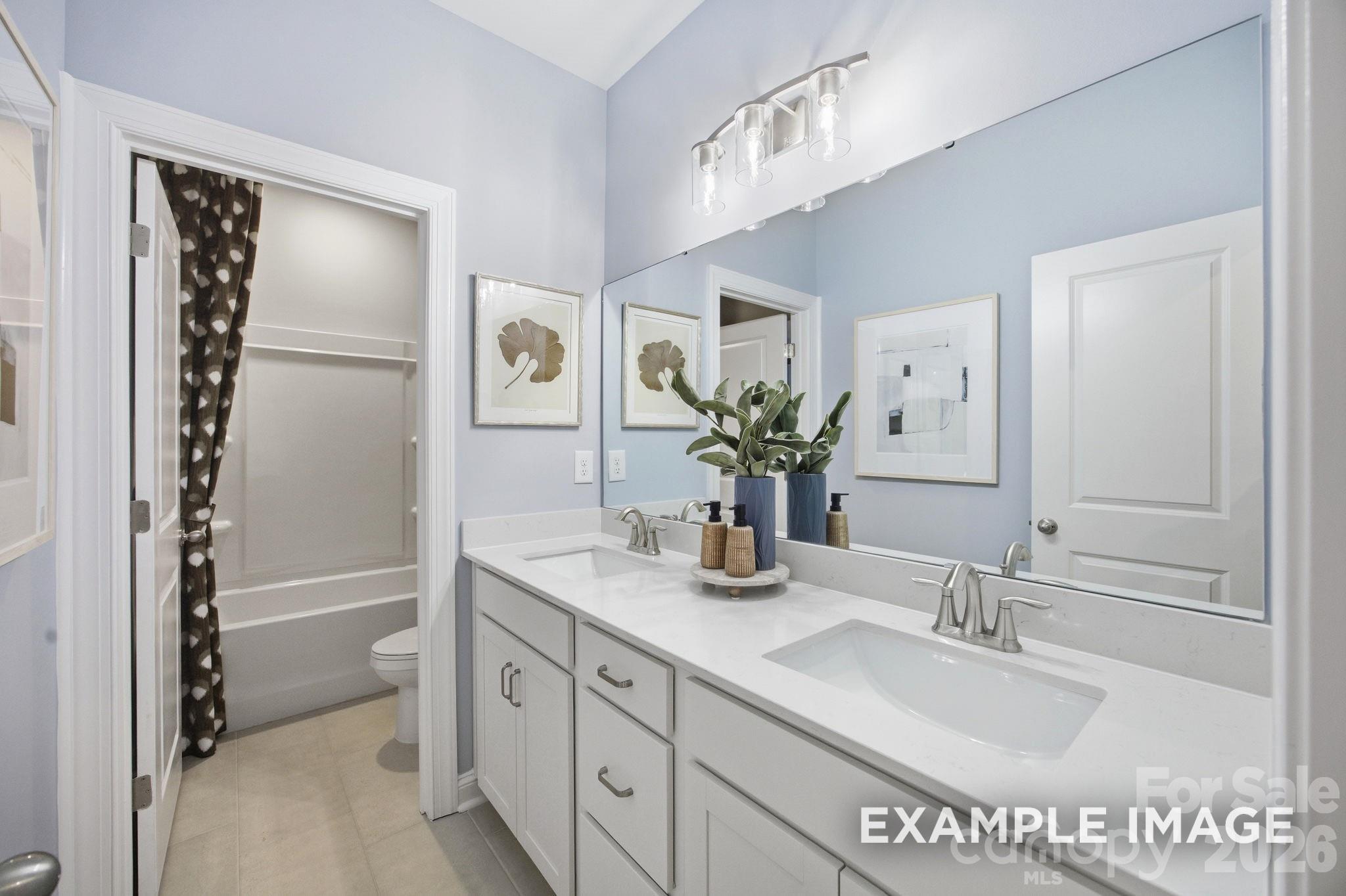 Modern bathroom with double vanity, quartz countertops, and tub-shower combo in Davidson Homes The Hickory B II, Mooresville.