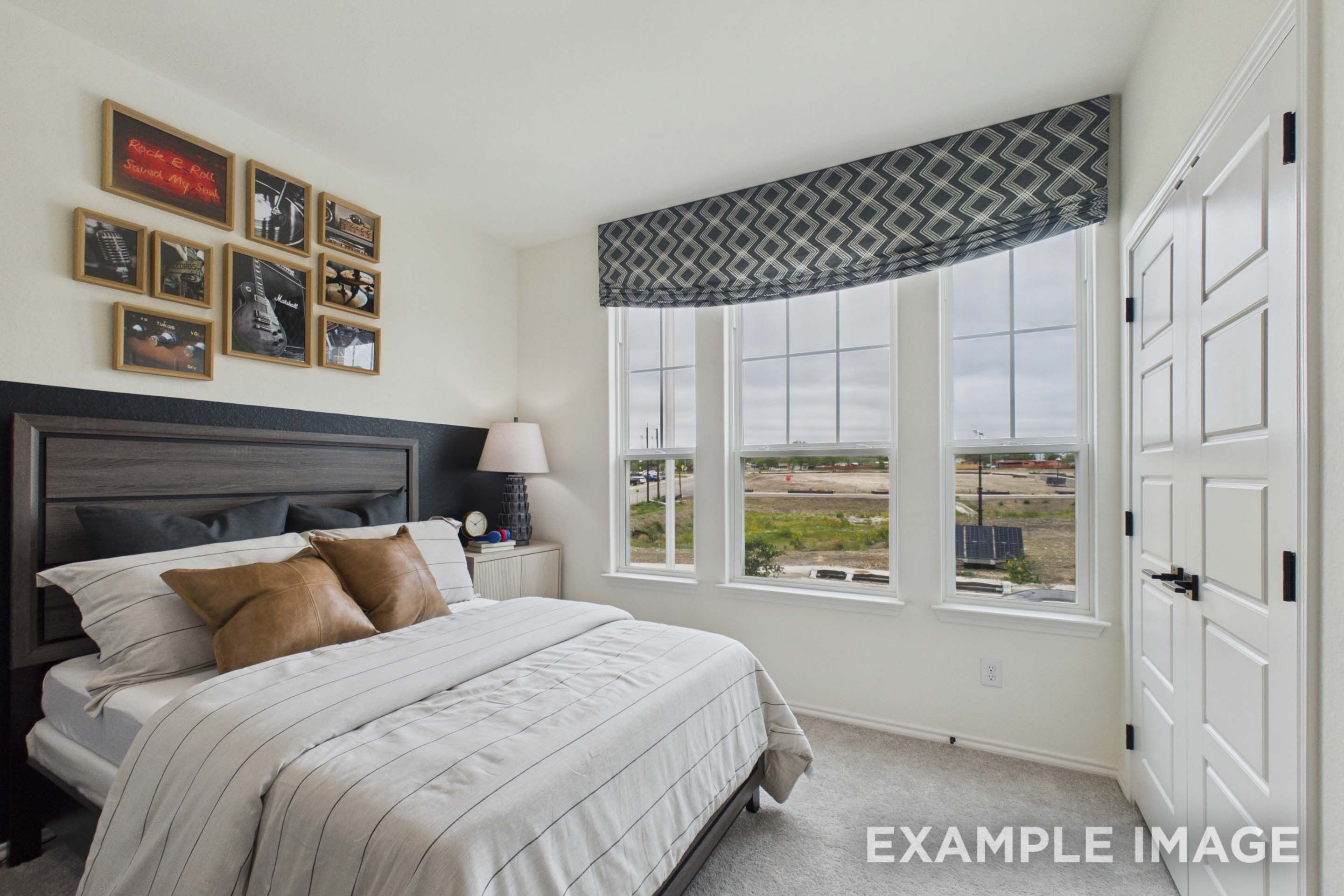 Spacious bedroom in The Laurel G floor plan featuring modern decor, large windows, and a comfortable bed.