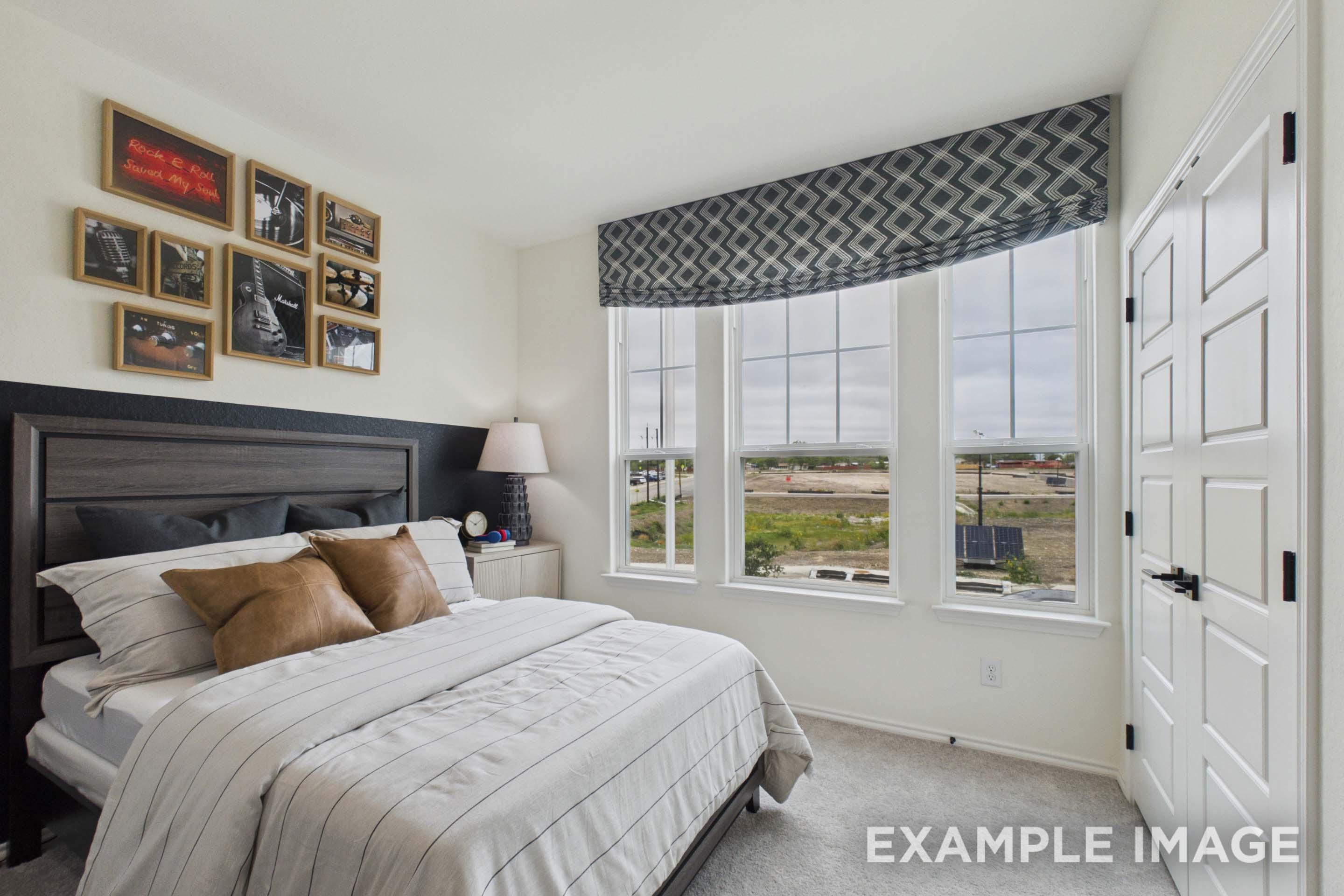 Spacious bedroom in The Laurel G floor plan featuring modern decor, large windows, and a comfortable bed.