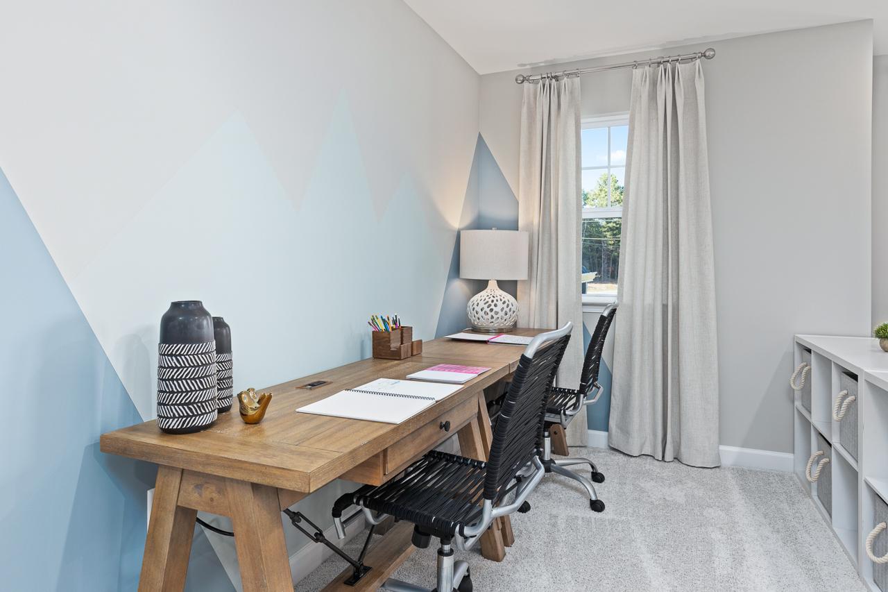 Home office area in The Hemlock featuring a double wood desk, mountain-themed wall mural, and storage cubbies.