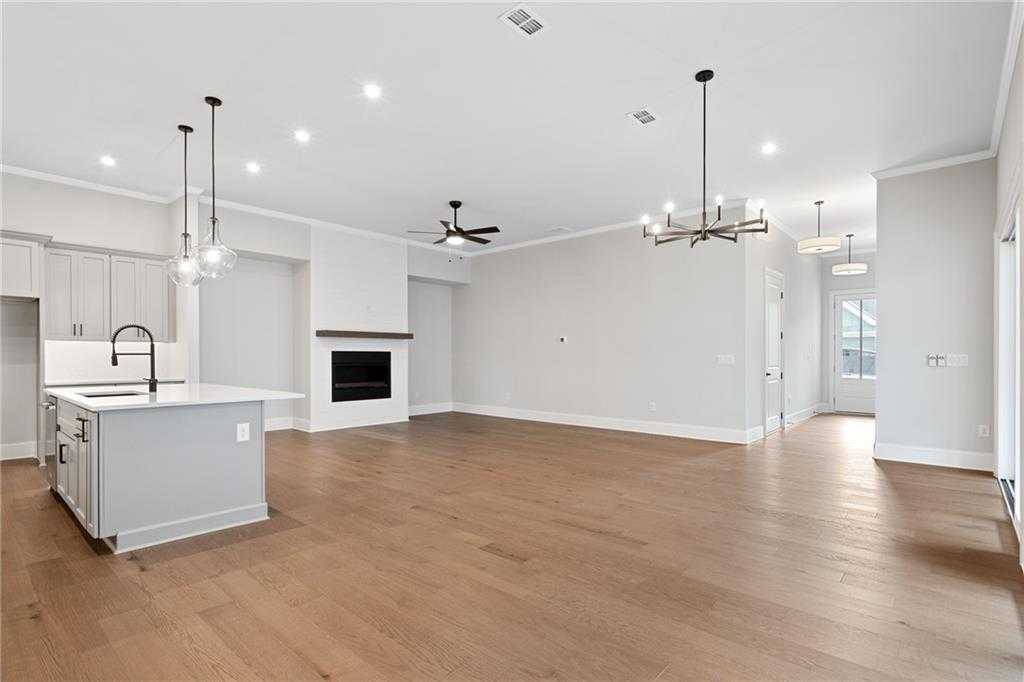 Open-concept kitchen-living area with gray island, white cabinets, wood floors, and modern fireplace in Davidson Homes Seaside B, Woodstock GA