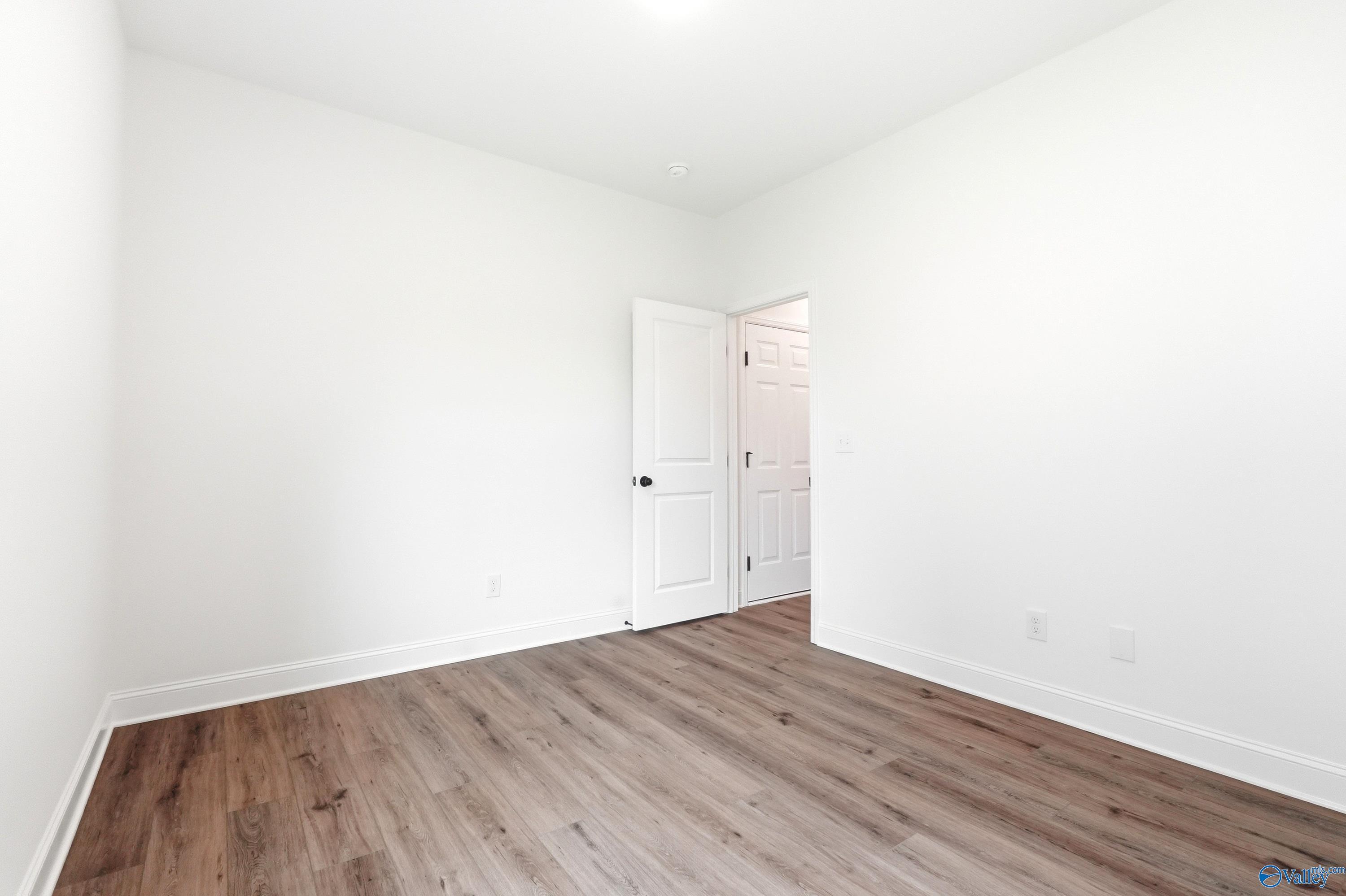 Bright, neutral bedroom with wood-look flooring in The Daphne C floor plan at Ivy Hills, Toney, Alabama.