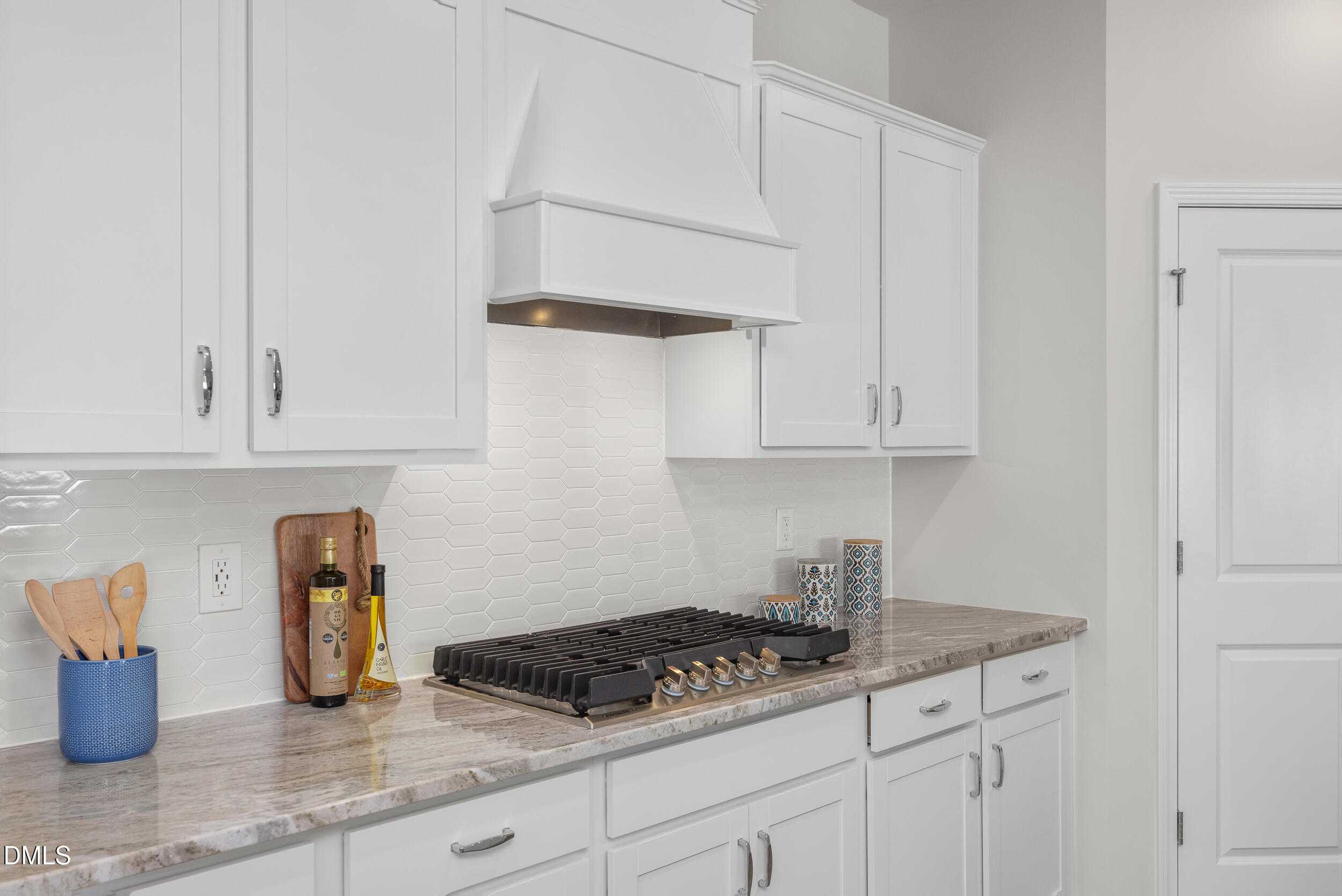 Modern white kitchen with shaker cabinets, gas cooktop, swirled granite counters in The Preston C by Davidson Homes, Lillington, NC
