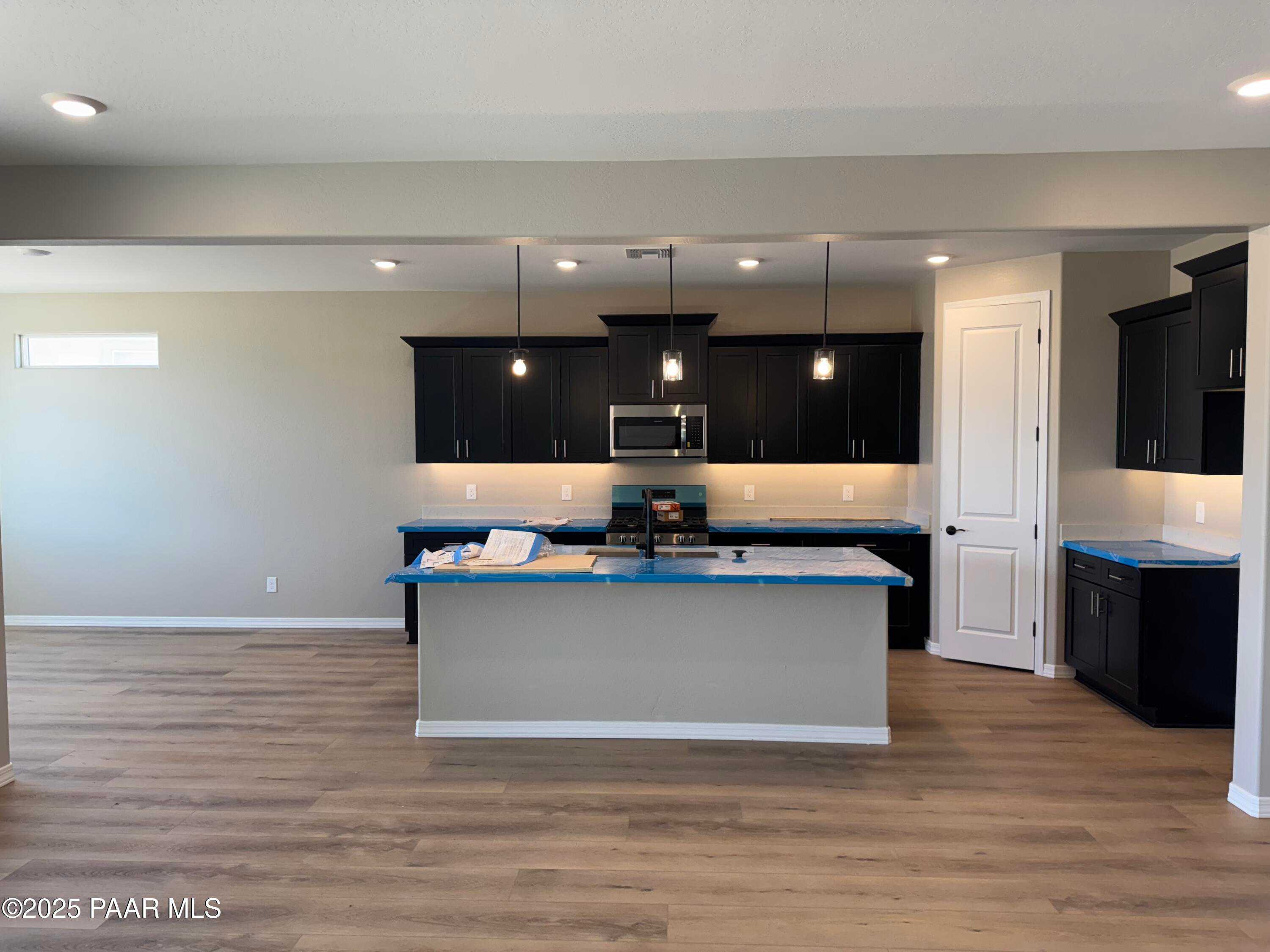 Modern open-concept kitchen with black cabinets, large island, stainless appliances in The Sheridan II B, Westwood, Prescott, AZ