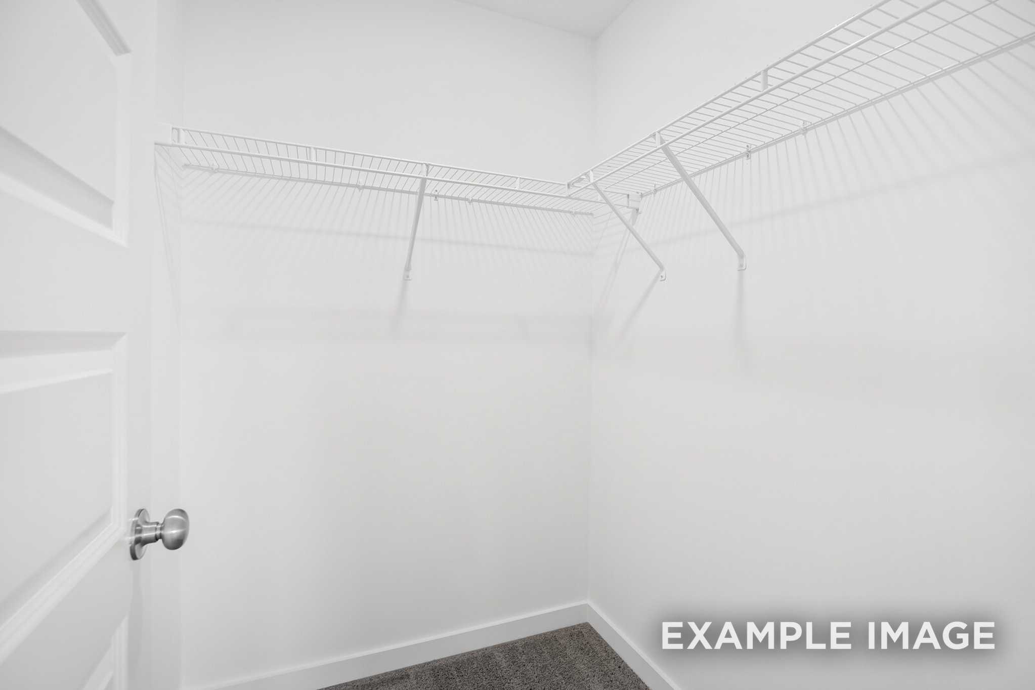 Spacious walk-in closet in The Murray B master suite featuring white wire shelving and neutral carpet flooring