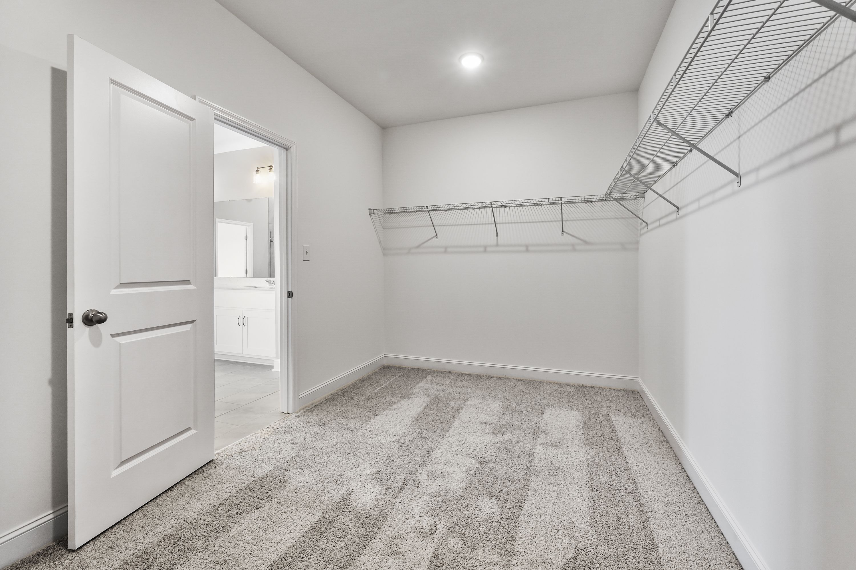 Spacious walk-in closet in The Valencia master suite with wire shelving, hanging rods, and adjacent bathroom access