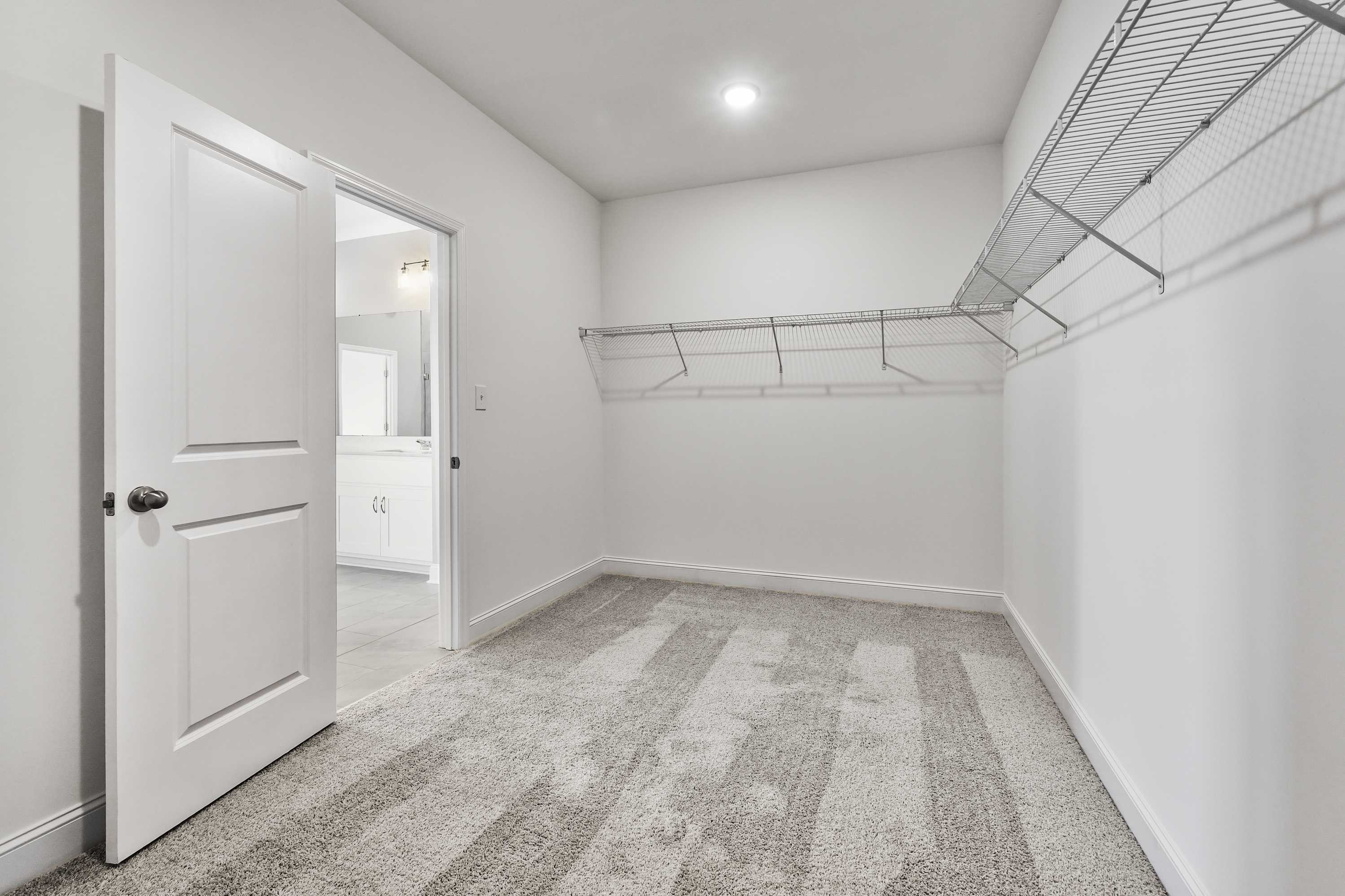 Spacious walk-in closet in The Valencia master suite with wire shelving, hanging rods, and adjacent bathroom access