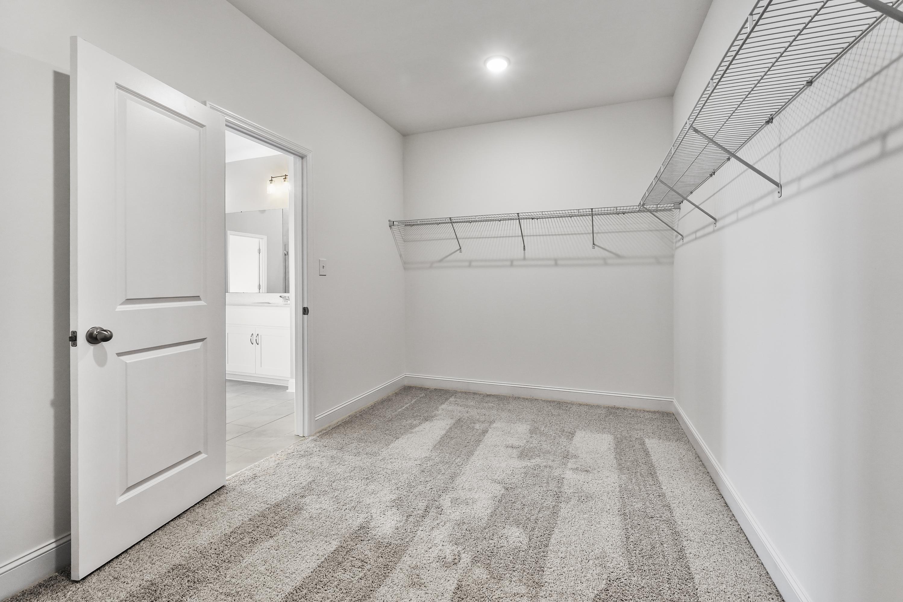 Spacious walk-in closet in The Valencia master suite with wire shelving, hanging rods, and adjacent bathroom access