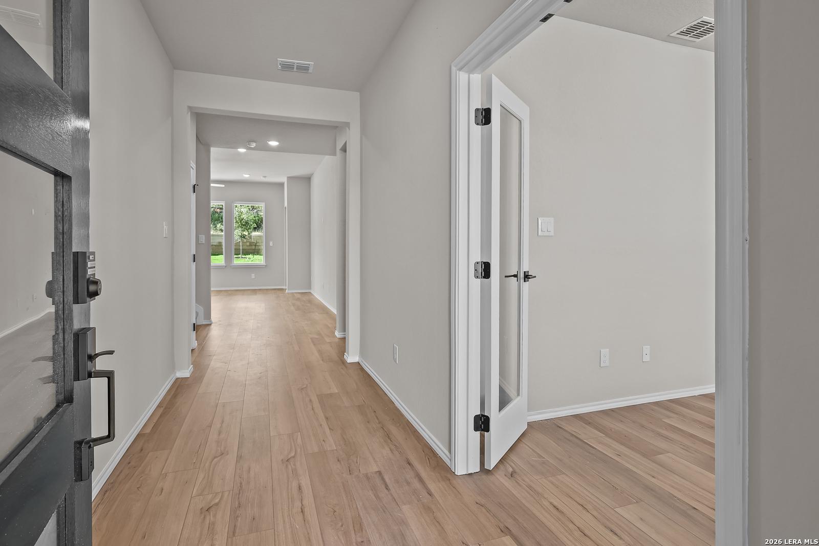 Foyer entry with wood-look plank flooring and glass-panel interior doors in Davidson Homes Sequoia C, Royal Crest, San Antonio