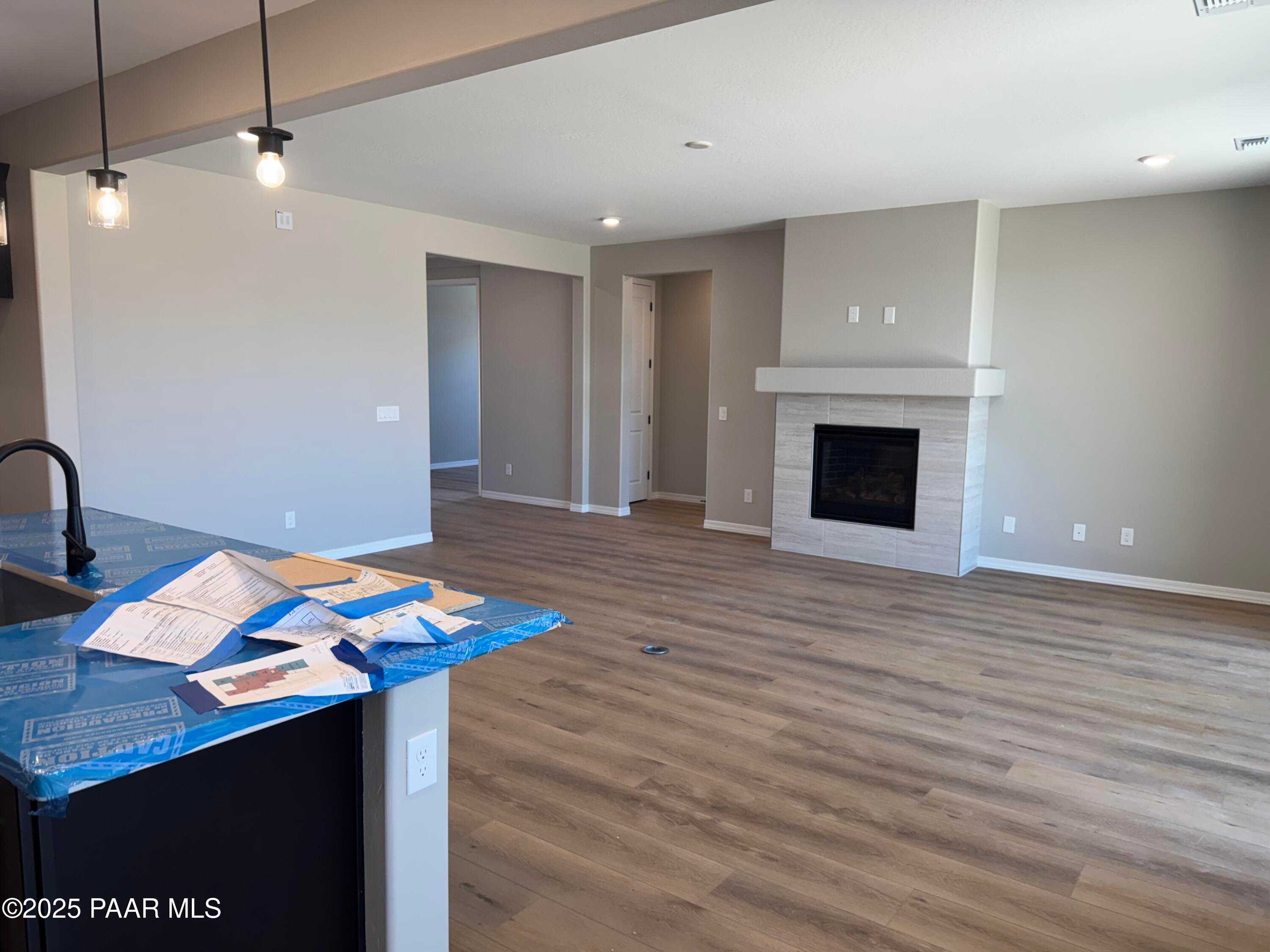 Spacious great room with stone gas fireplace, hardwood floors, and covered kitchen island in Davidson Homes The Sheridan II B, Prescott, AZ