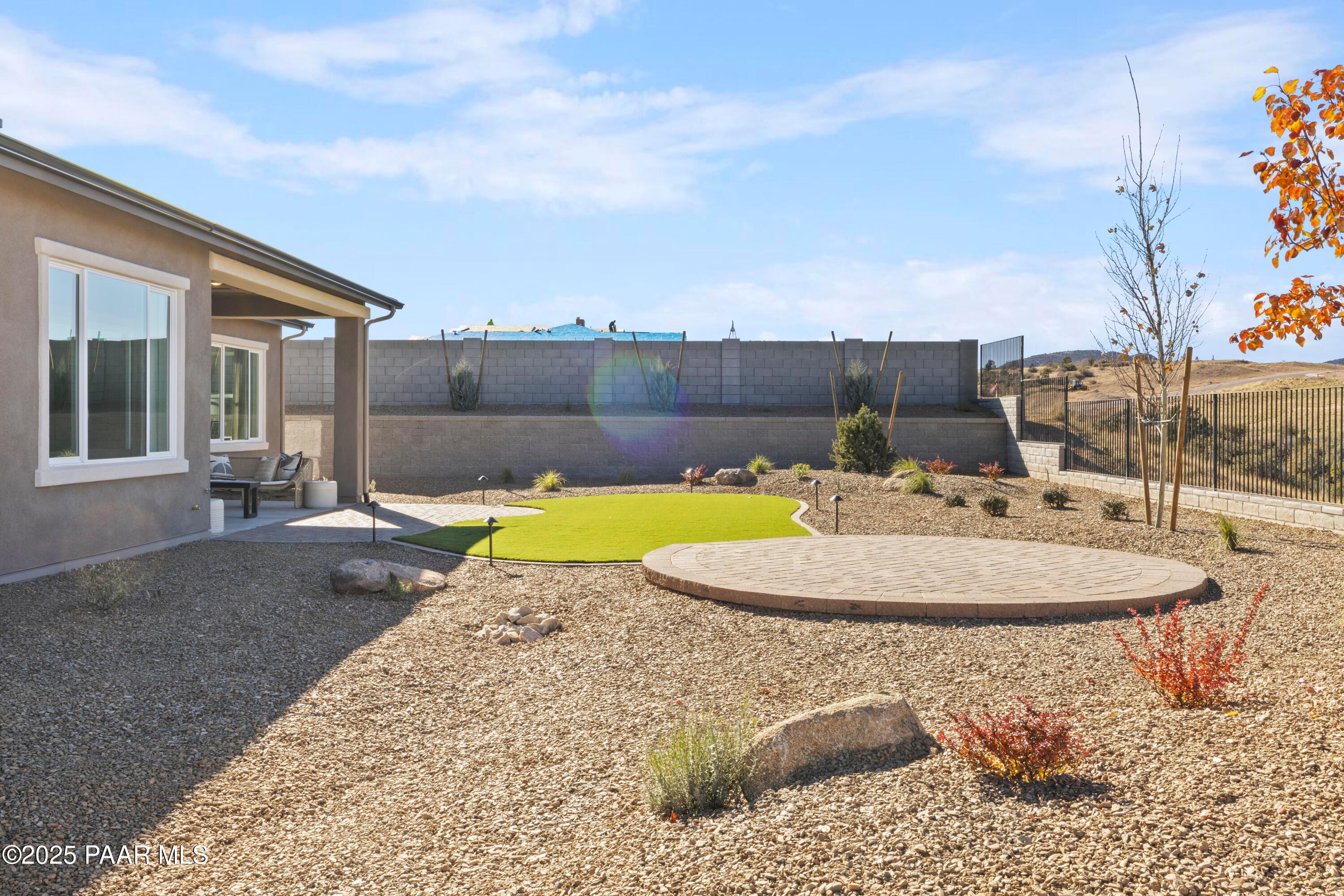Desert backyard with putting green, gravel landscaping, native shrubs, and covered patio in Hidden Hills Prescott AZ home