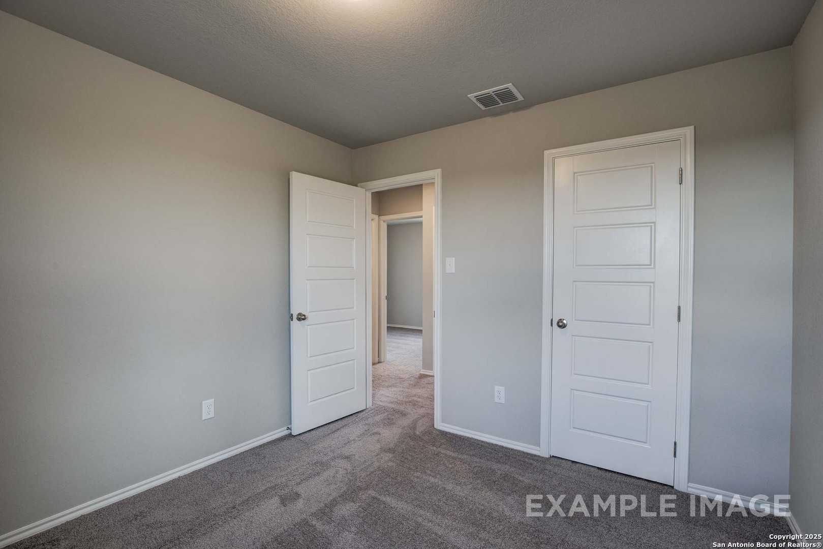 Neutral bedroom with beige walls, white paneled doors, carpet floor in Davidson Homes The Blanco C, Agave, San Antonio, Texas
