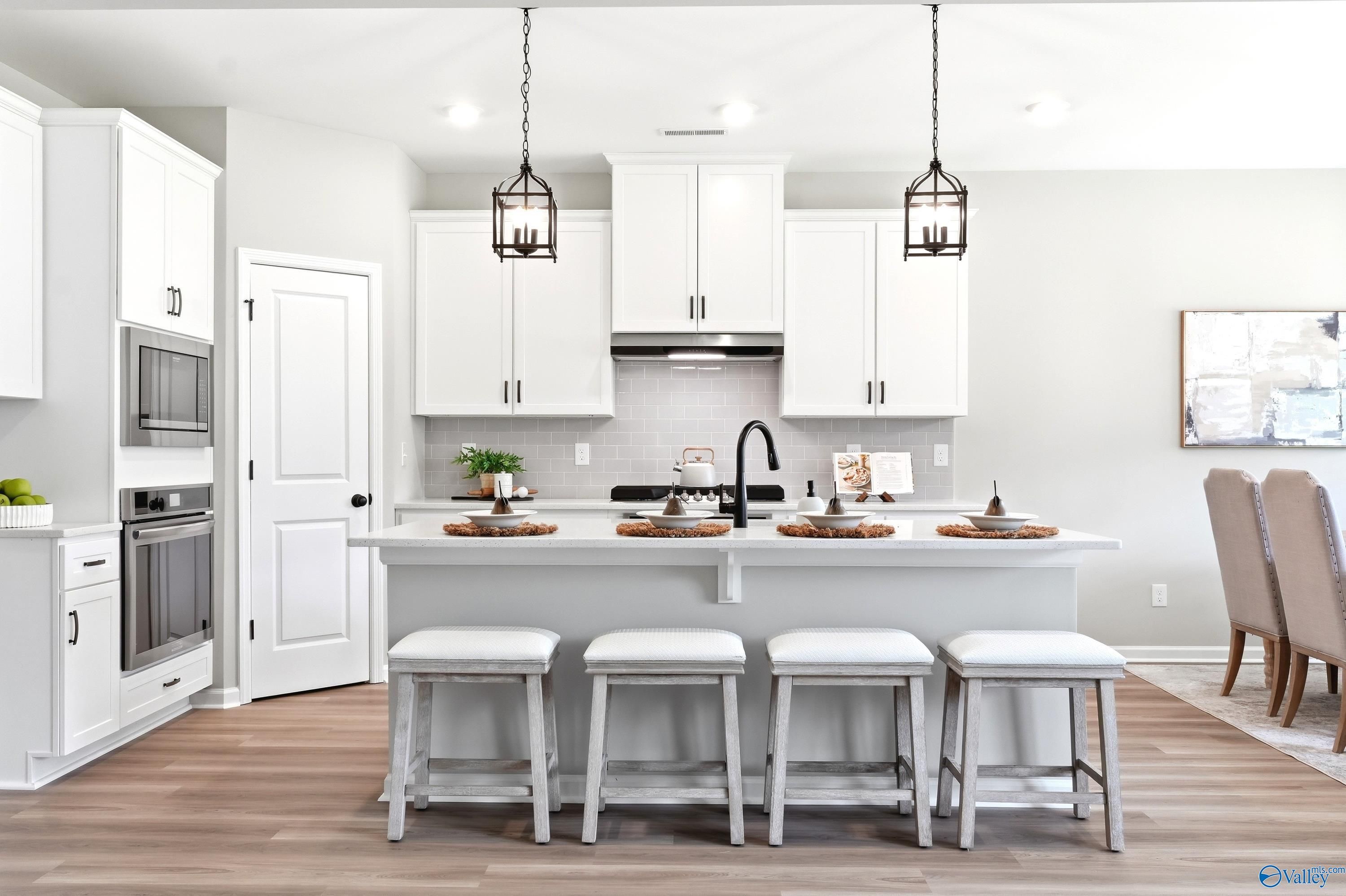 Modern kitchen with white cabinets, island seating, and stainless appliances in The Dorado floor plan at Riverton Preserve.