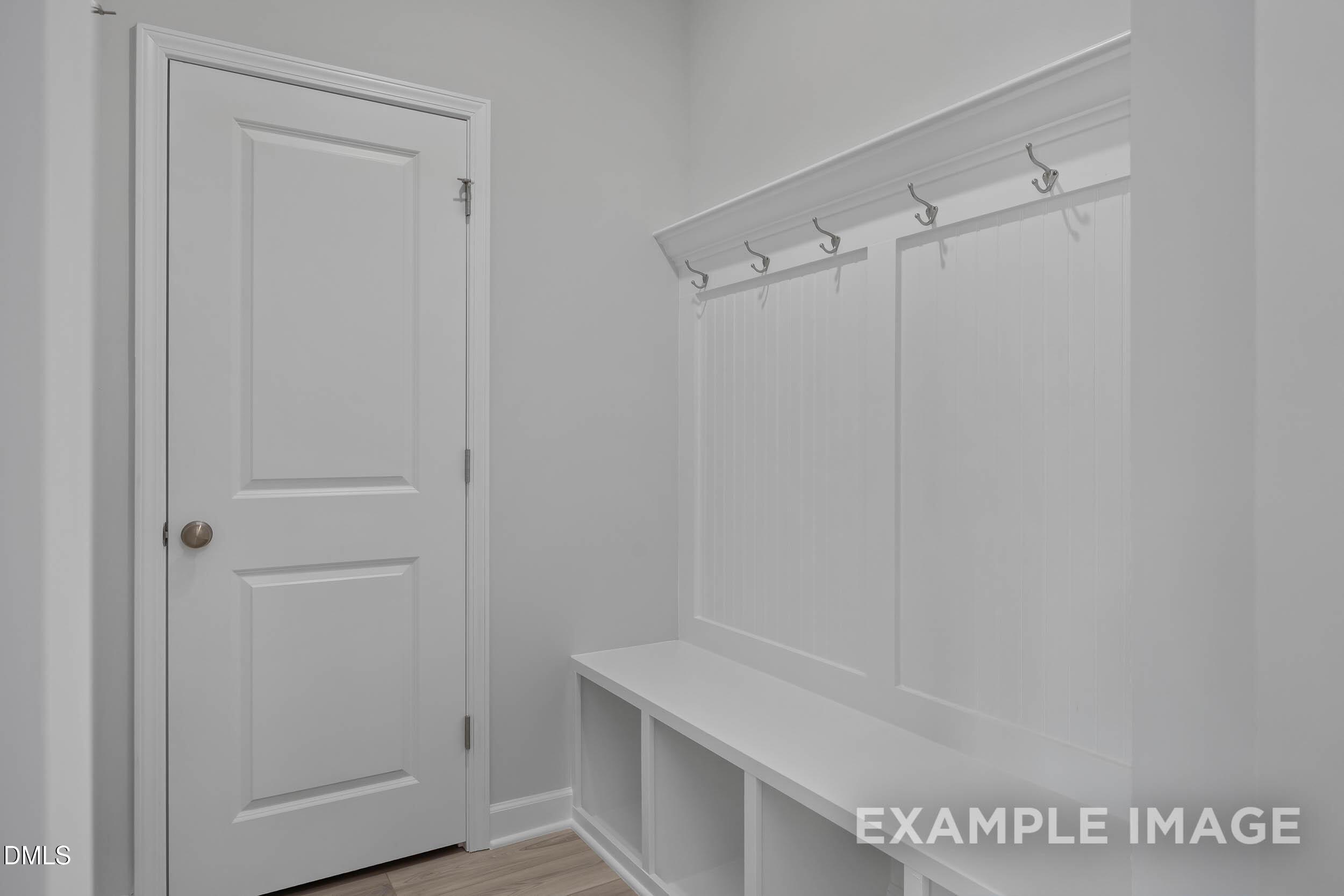 White mudroom drop zone with built-in bench and coat hooks in The Magnolia A floor plan at Retreat at North Main.