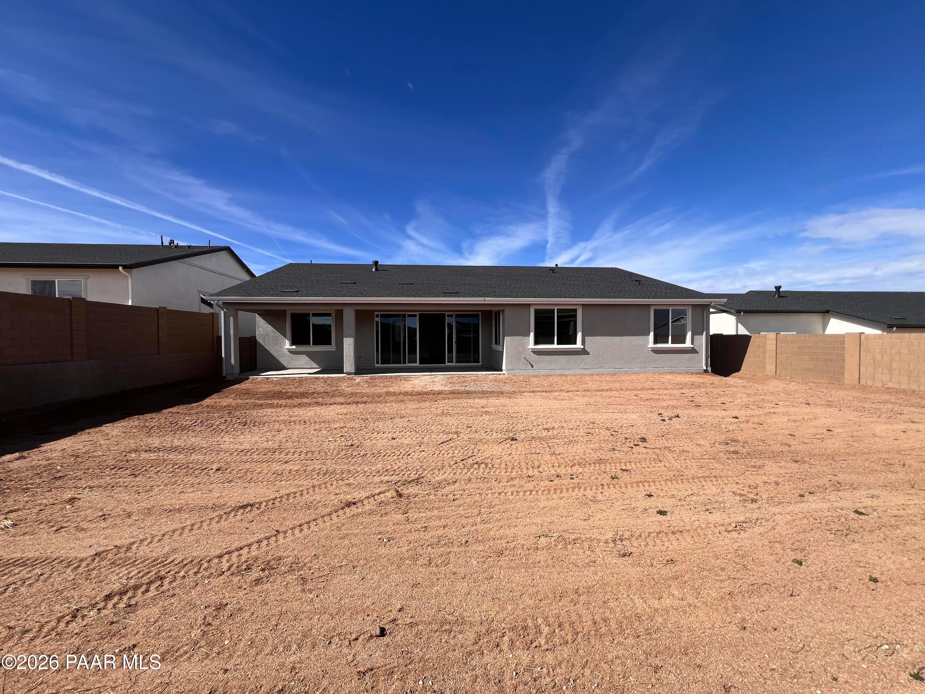 Rear view of single-story The Monarch A home by Davidson Homes in Westwood, Prescott, Arizona, with sliding doors to dirt backyard
