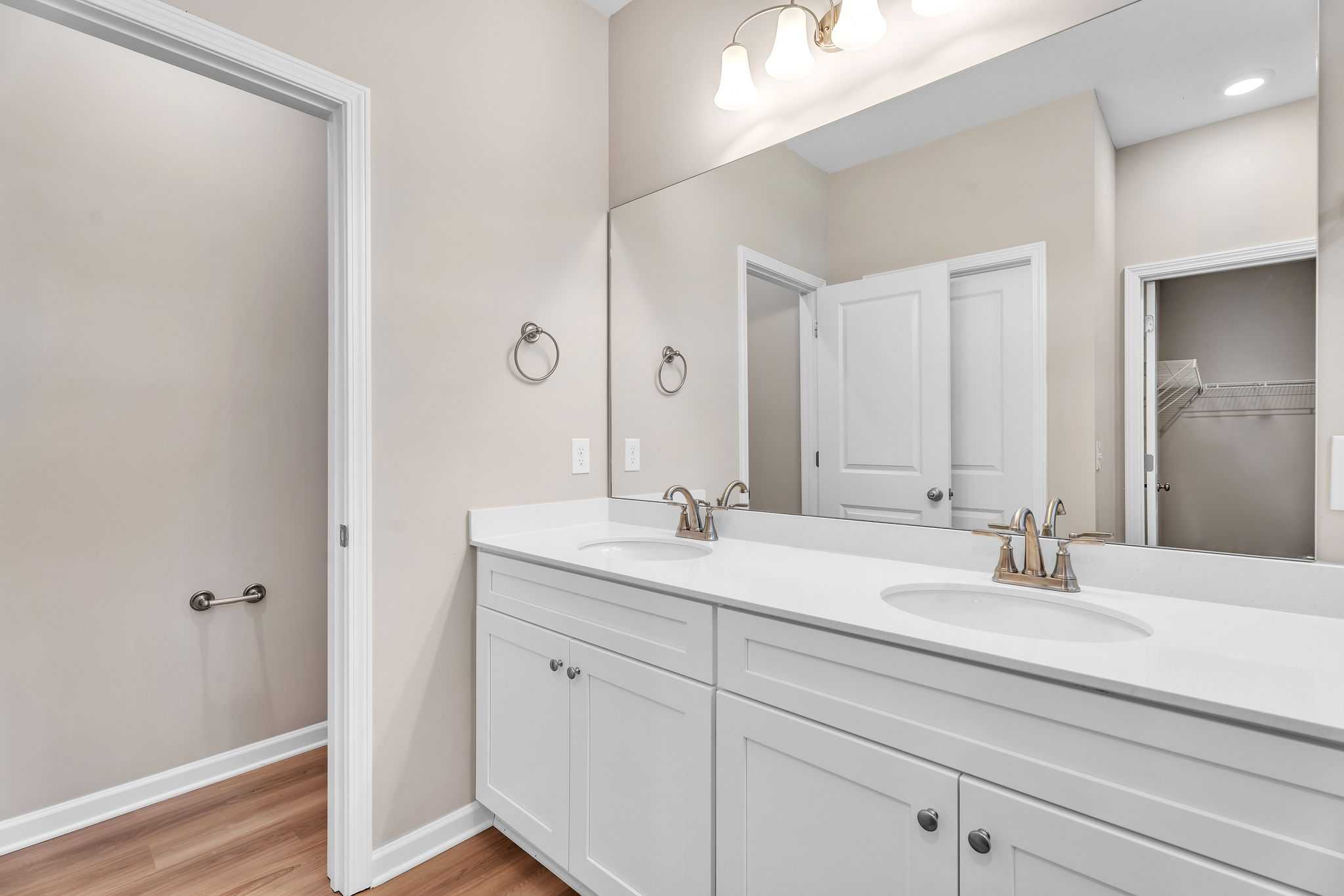 Spacious master bathroom at Anderson Lakes in Opelika Alabama featuring double vanity white cabinets quartz counters and hardwood floors