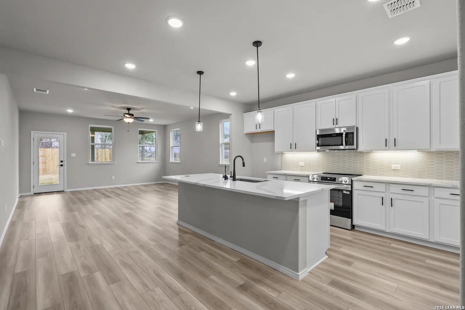 Modern kitchen with white cabinets, quartz island, and open-concept floor plan in The Glenwood E, Comanche Ridge, San Antonio.