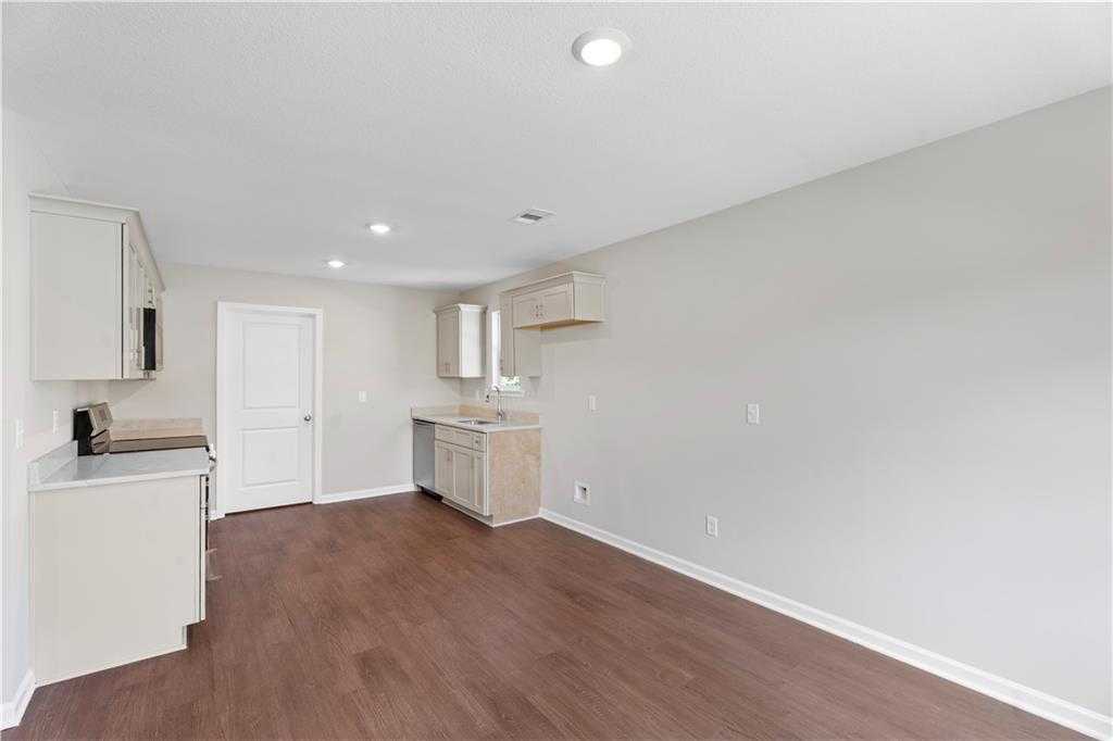 Modern laundry room with white cabinets, deep utility sink, and hardwood floors in Davidson Homes The Washington, Phenix City