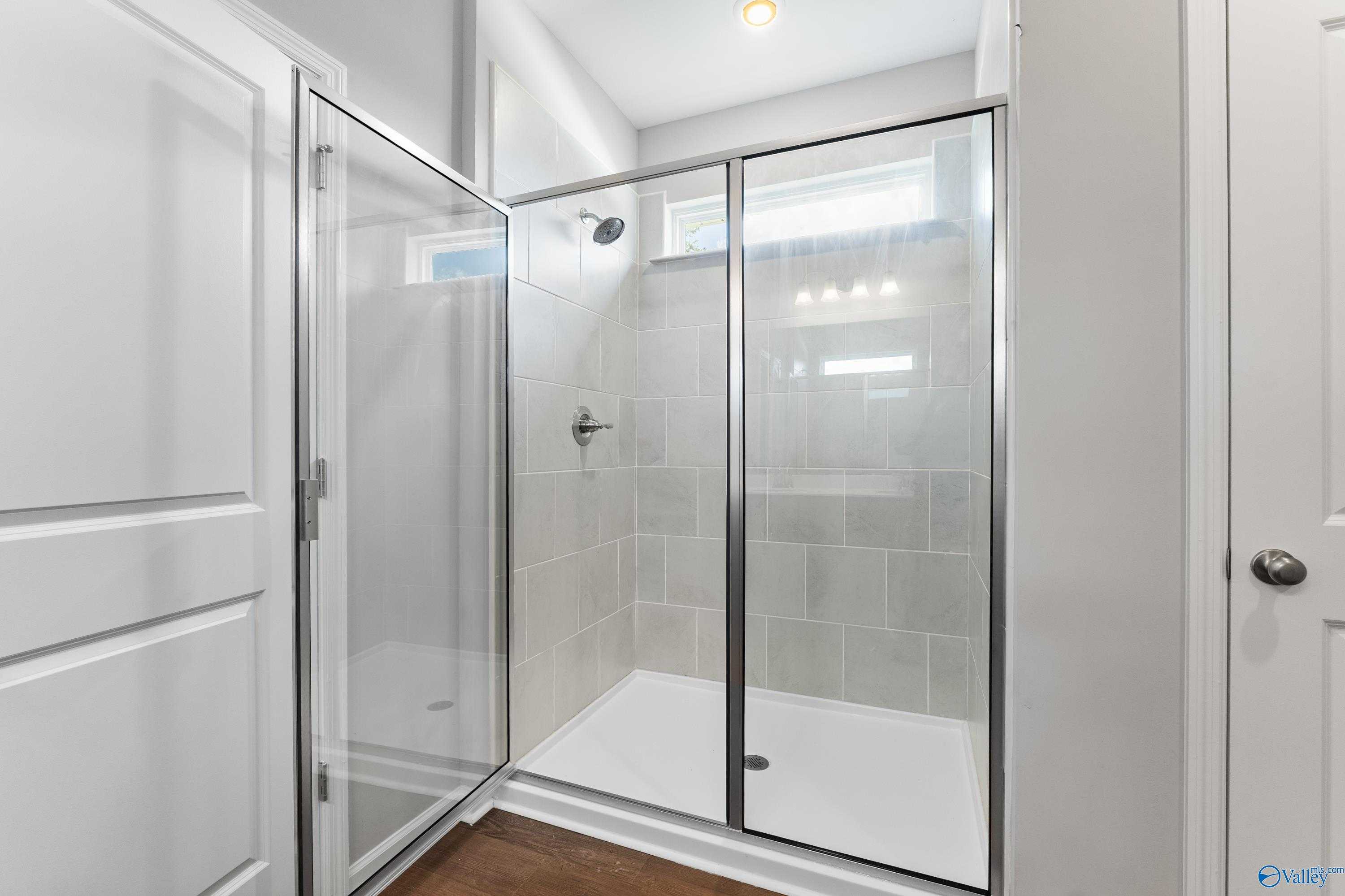 Modern master bath with frameless glass shower, subway tile walls, and rainfall head in Davidson Homes The Sanctuary, Huntsville, AL