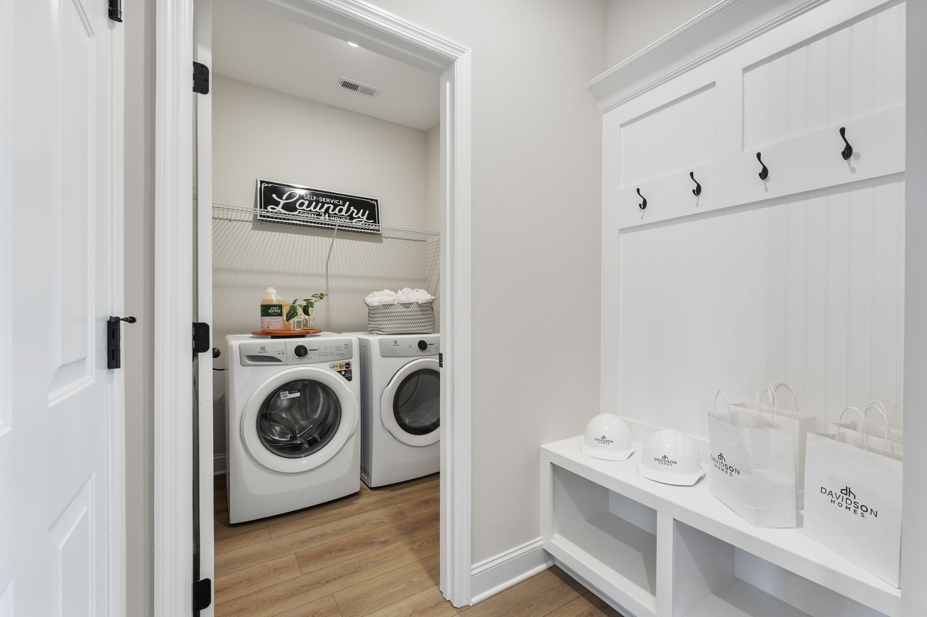 Spacious laundry room at Ramsay Cove in Owens Cross Roads AL with white shiplap cabinets, washer dryer, hardwood floors, and built-in shelves