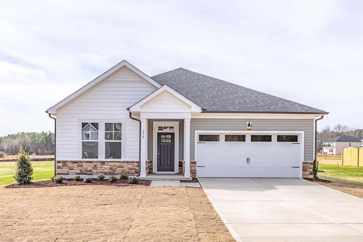 Modern craftsman home exterior at Wellers Knoll in Lillington NC with white siding, brick base, covered porch, and two-car garage