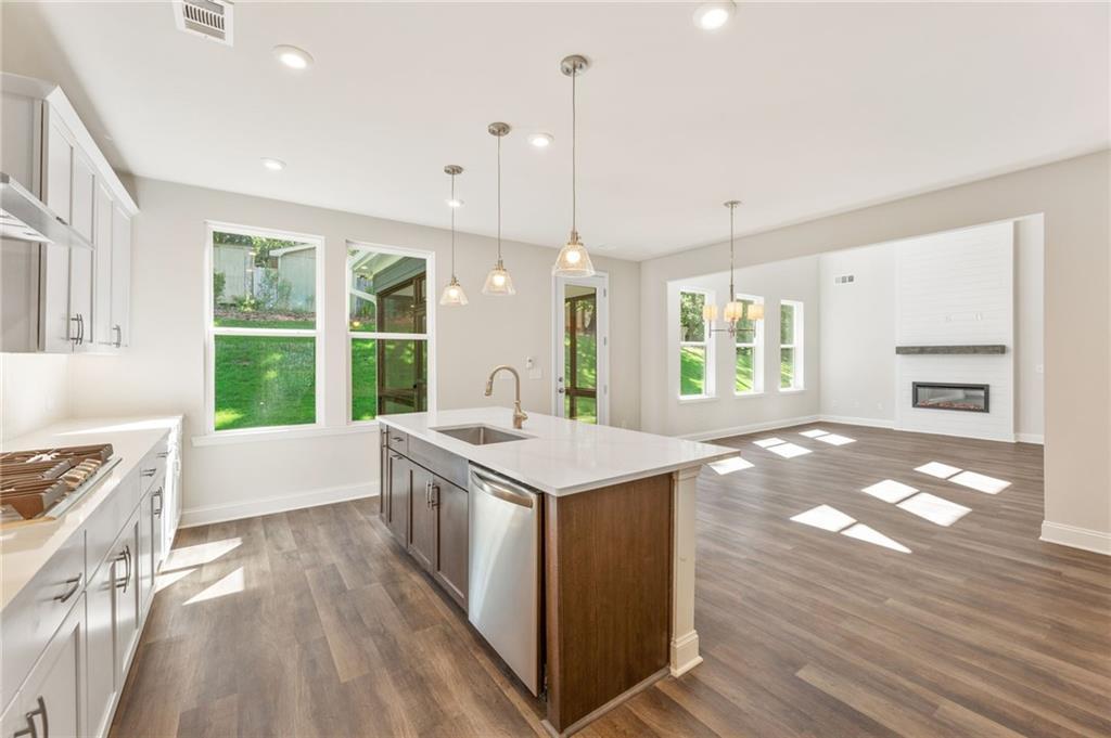 Modern open-concept kitchen with white island sink, stainless appliances, and fireplace in Davidson Homes The Danbury E, Buford, GA