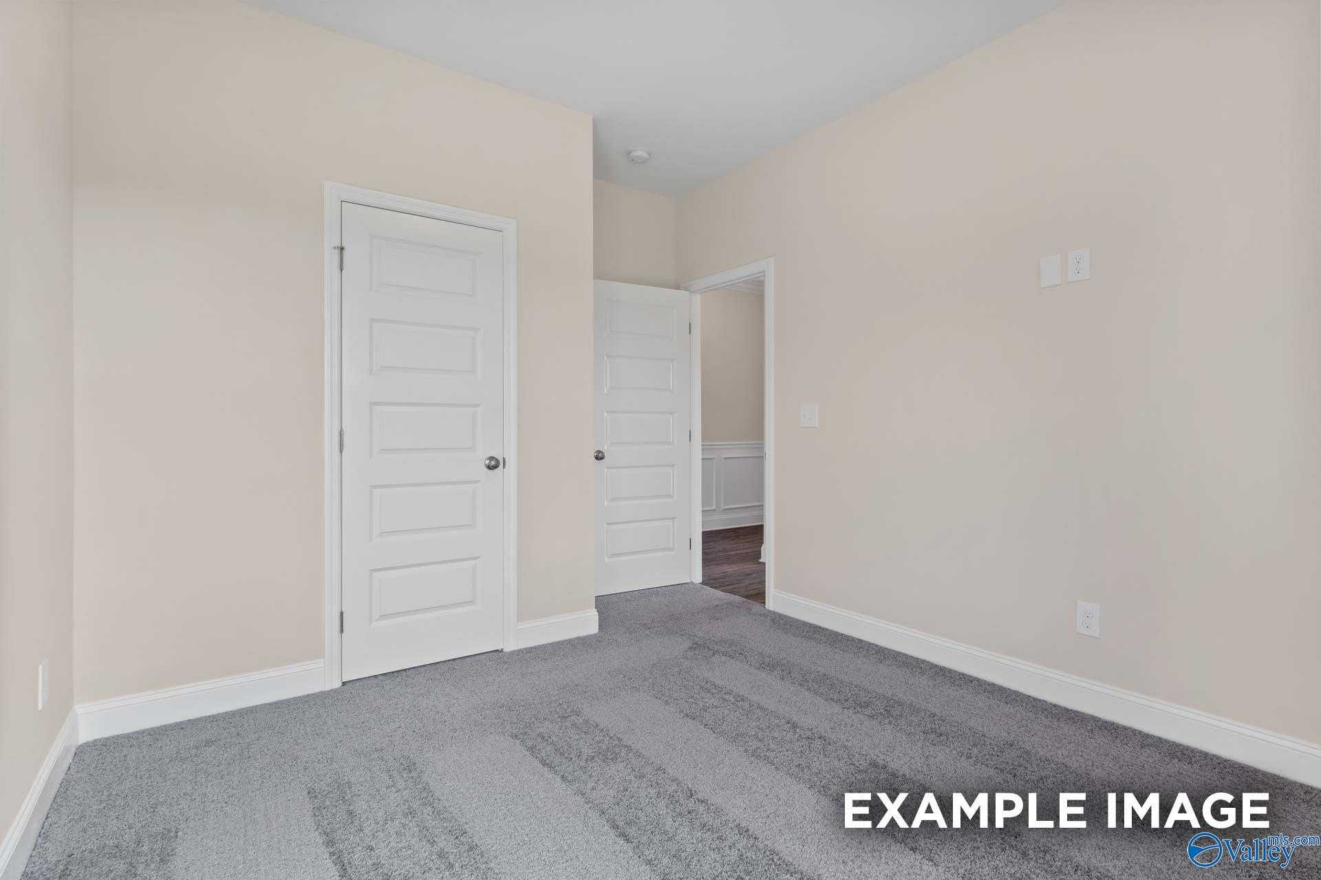 Empty secondary bedroom with beige walls, gray carpet, and adjacent bath door in The Asheville plan by Davidson Homes, Arab AL